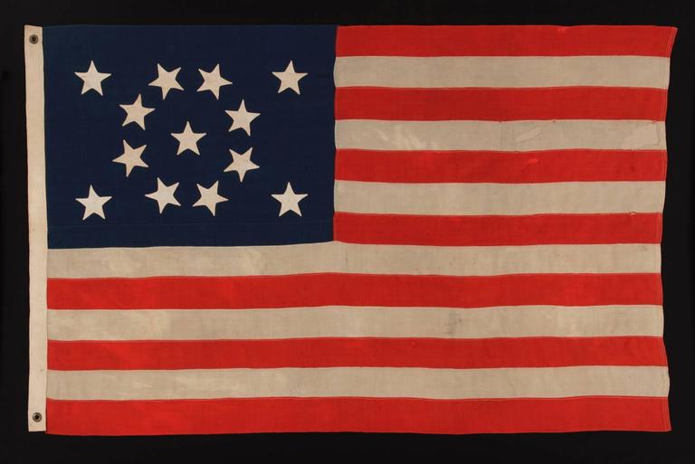 13 HAND-SEWN STARS IN A BEAUTIFUL MEDALLION CONFIGURATION ON A SMALL SCALE ANTIQUE AMERICAN FLAG OF THE 1876 CENTENNIAL ERA: 

13 star American national flag, made around the time of the 1876 centennial of American independence. The stars are