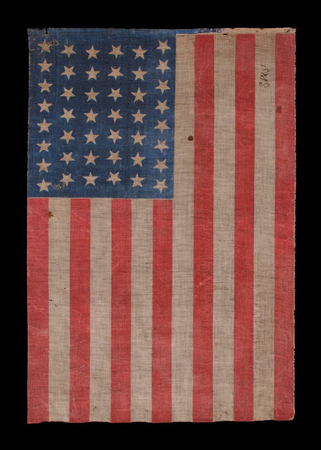 44 STARS IN DANCING ROWS IN AN HOURGLASS FORMATION, ON AN ANTIQUE AMERICAN PARADE FLAG, 1890-1896, REFLECTS WYOMING STATEHOOD:

44 star American parade flag, printed on coarse, glazed cotton. The stars are configured in rows of 8-7-7-7-7-8, with the