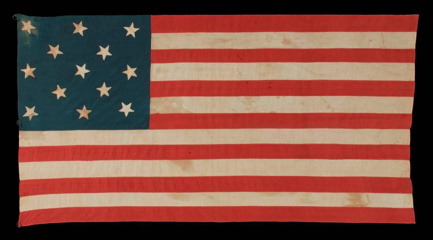 13 hand-sewn stars arranged in a 3-2-3-2-3 pattern, with varying vertical orientation, on a homemade antique American flag dating to the era of the 1876 centennial of American independence:

13 star American national flag, made around the time of