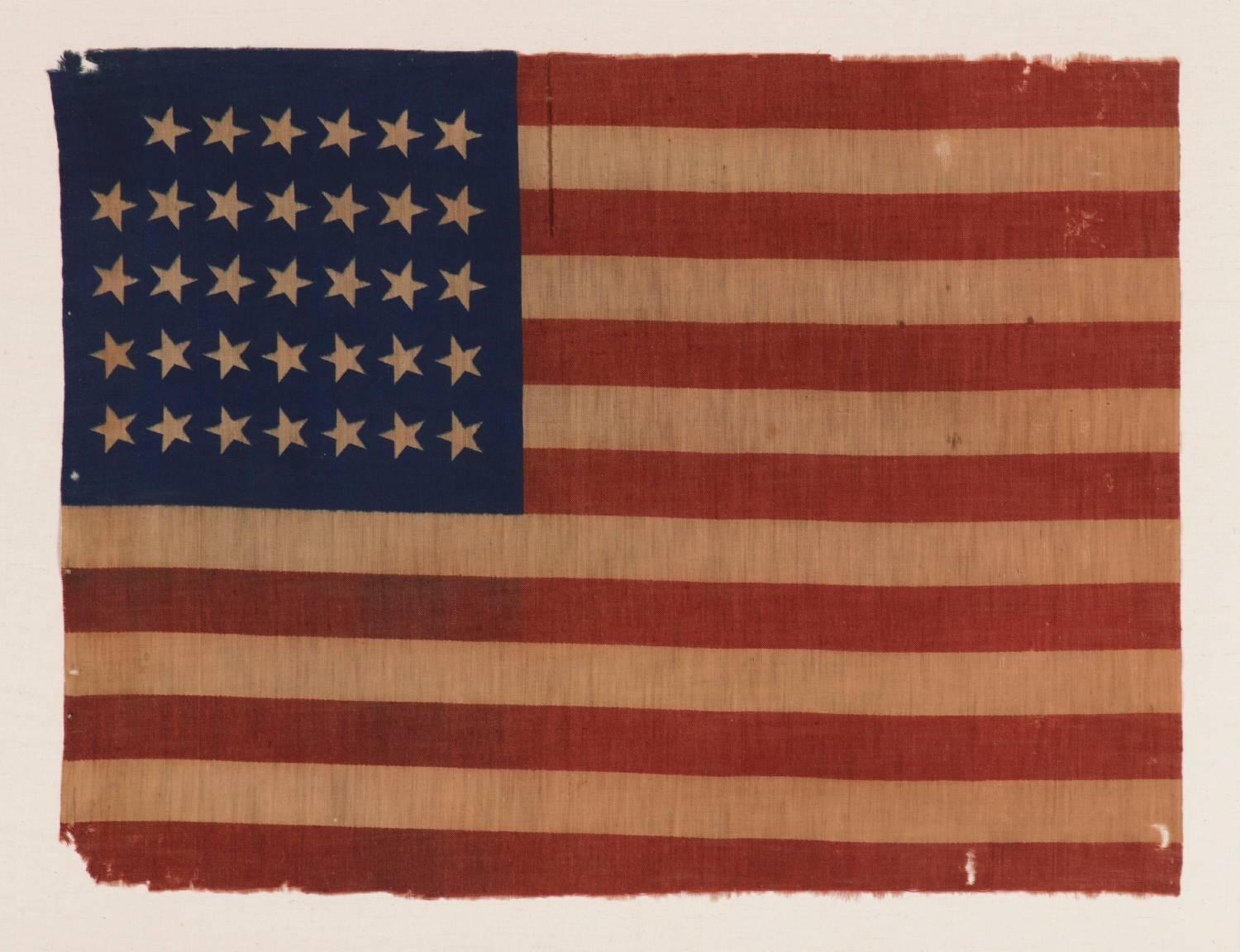 34 STARS, CIVIL WAR PERIOD, PRINTED ON A WOOL BLENDED FABRIC, RARE NOTCHED DESIGN WITH TILTED STARS, POSSIBLY A UNION ARMY CAMP COLORS:

34 star American national flag, printed on a wool and cotton blend. The star configuration, which leaves a