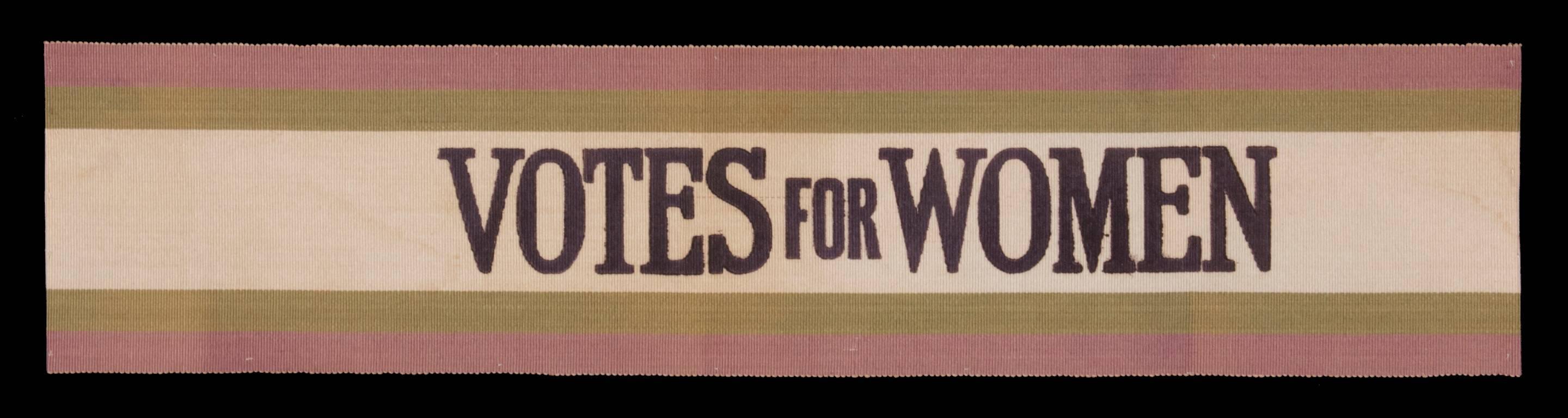 Section of wide silk ribbon, of the type often worn as a sash, with green and purple striping and printed black text that reads 