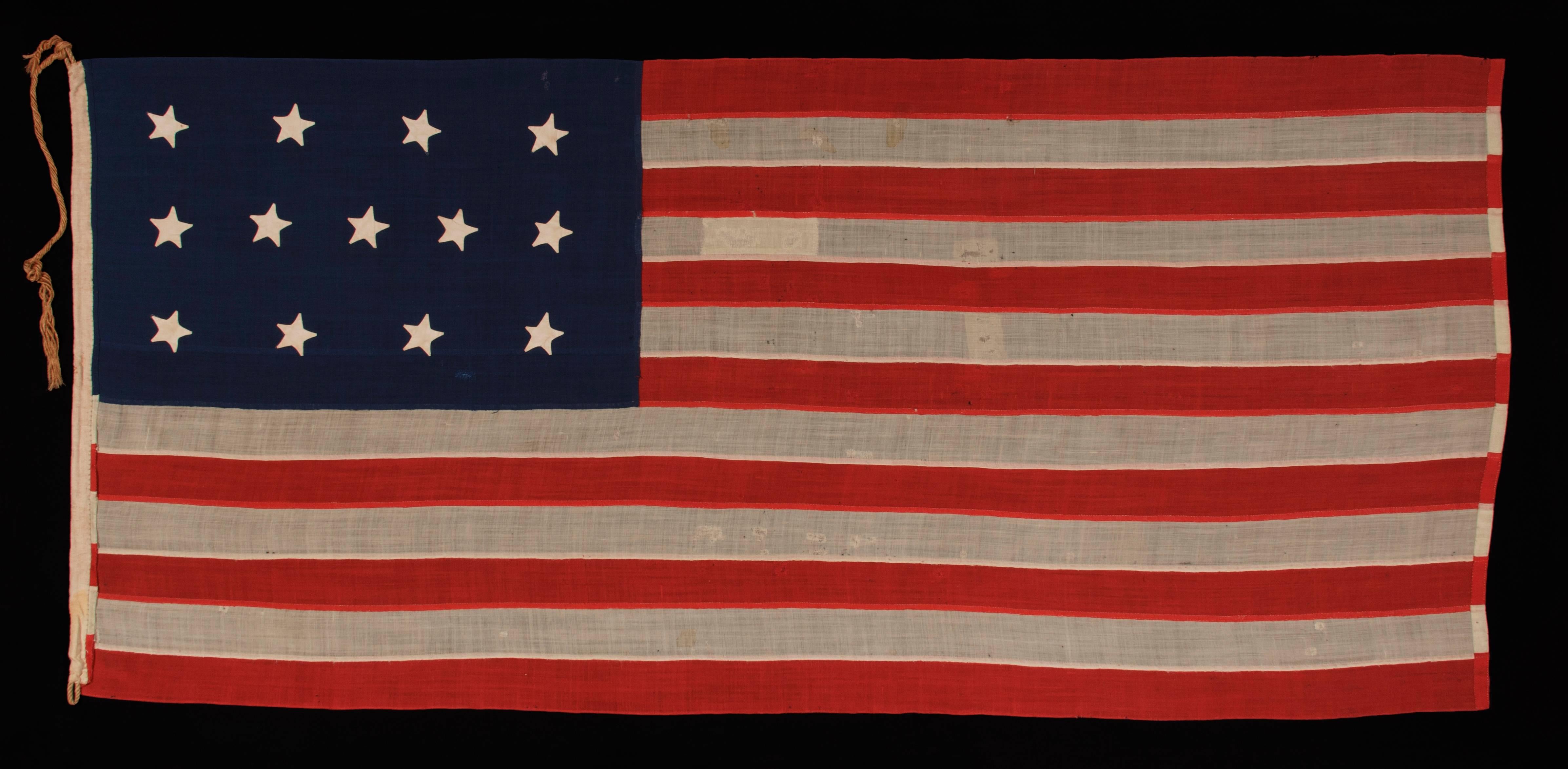 ENTIRELY HAND-SEWN, 13 STAR, U.S. NAVY SMALL BOAT ENSIGN WITH A 4-5-4 CONFIGURATION, MADE SOMETIME BETWEEN 1850 AND THE OPENING YEARS OF THE CIVIL WAR (1861-63): 

U.S. Navy small boat ensign with 13 stars arranged in a 4-5-4 pattern of lineal rows.