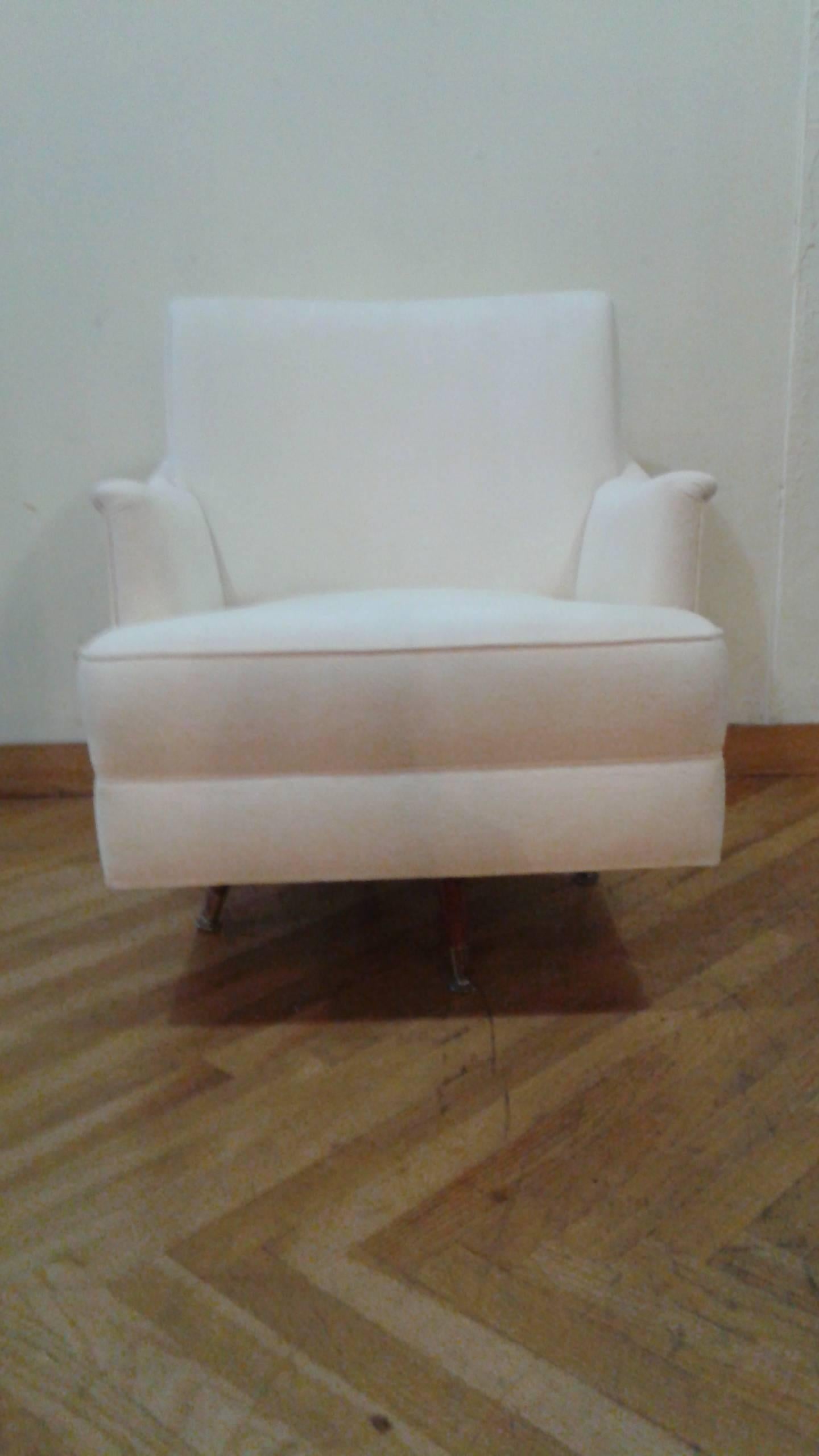 A pair of white Mid-Century swivel armchairs with walnut and brass legs.