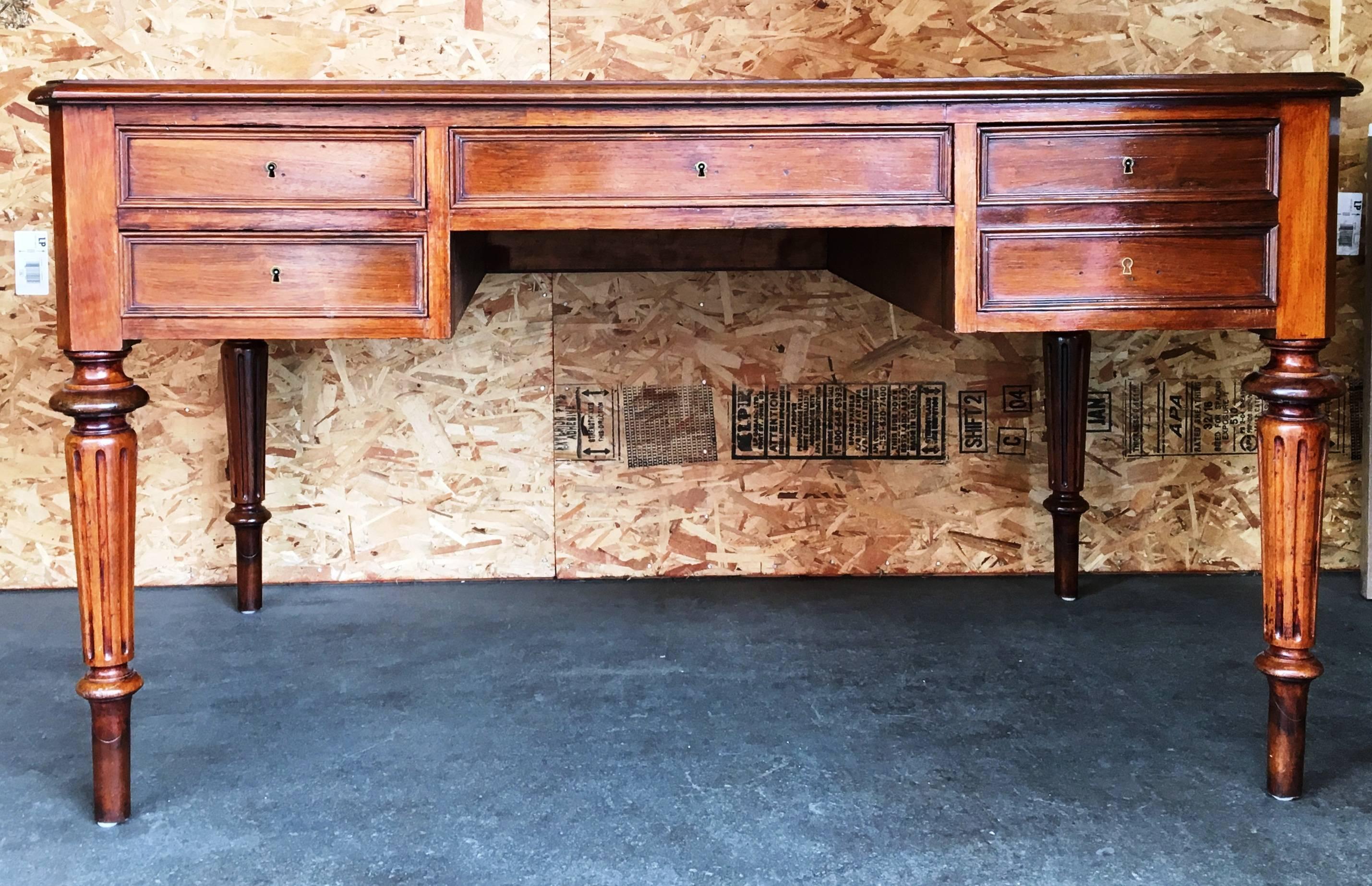 Antique five-drawer desk with a leather top and detailed turned legs. 