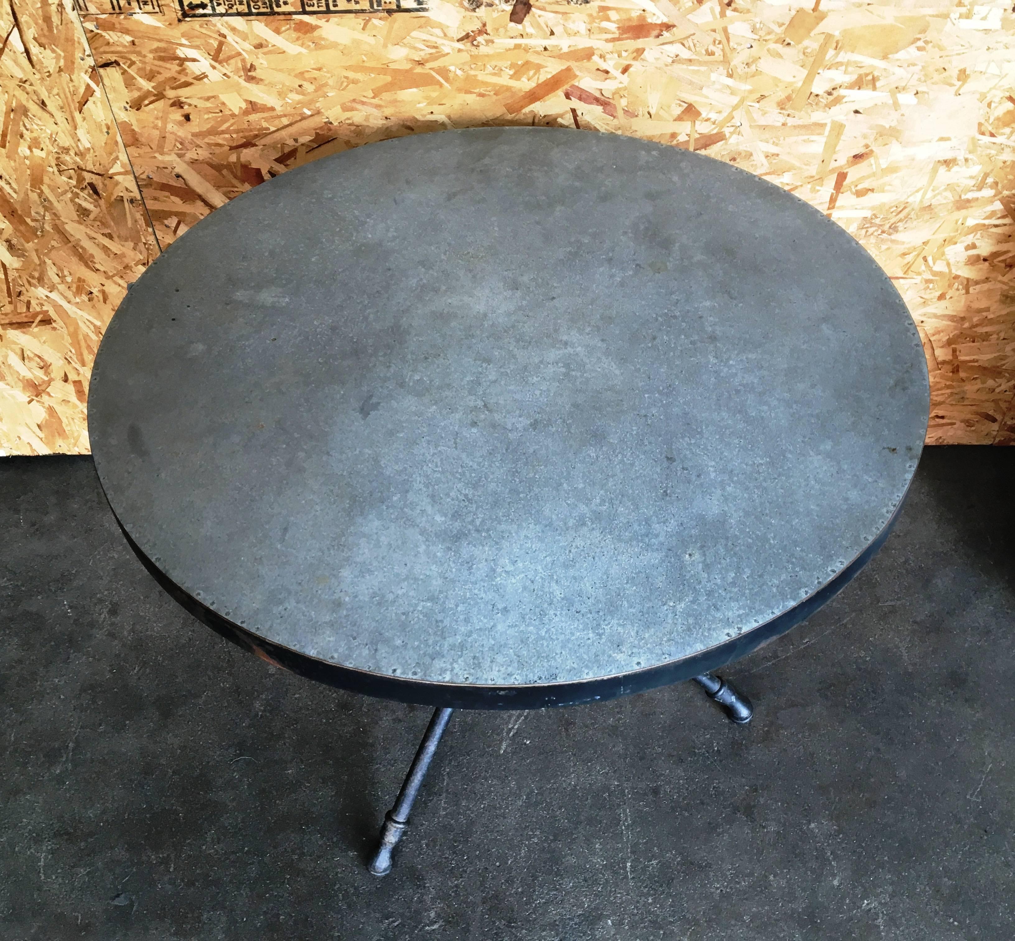 Three-leg metal table base with a poured concrete top.