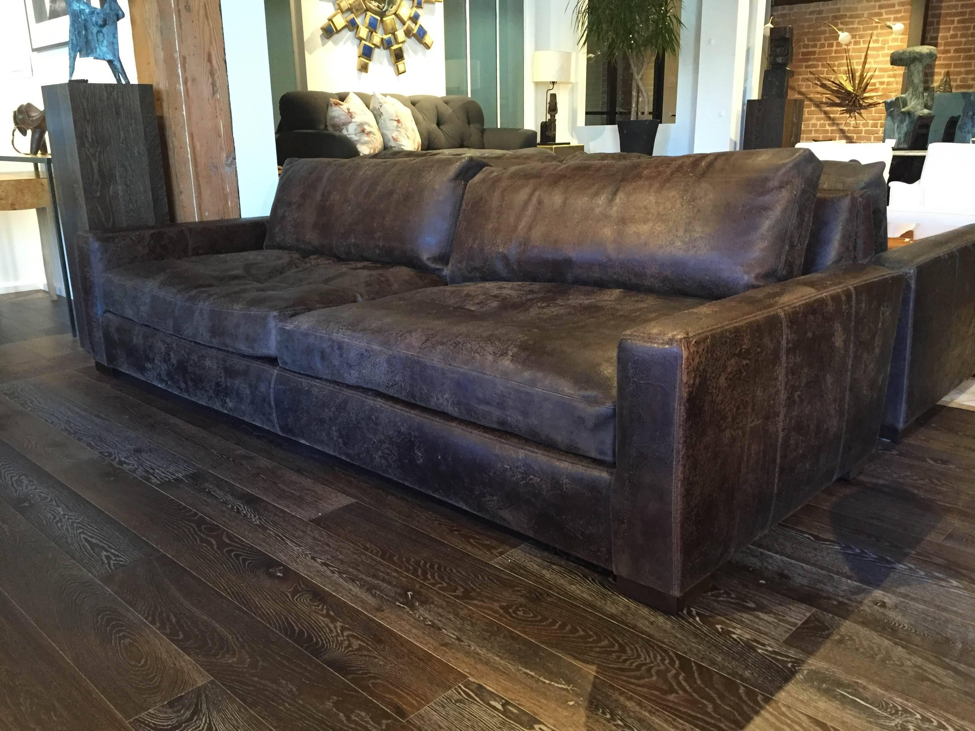 Streamlined sofa with a low back. Seat and back cushions are wide and squared-off. Upholstered in dark distressed leather.