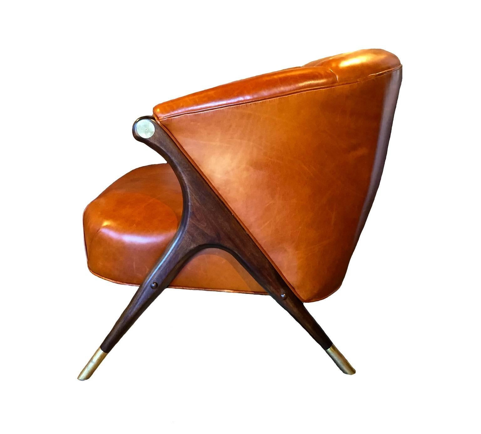 A pair of modern lounge chairs created by the Karpen Company of California. Strong wooden legs with brass accents compliment the channeled cognac leather. 