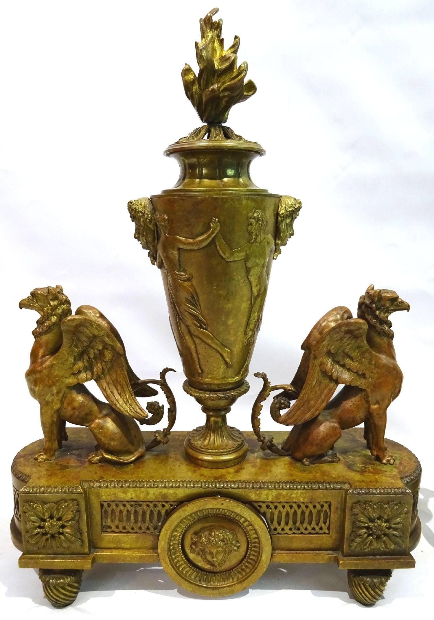 Pair of Louis XIV style bronze andirons attributed to Ferdinand Barbedienne (1810-1892), in a patinated finish, consisting of a centrally located upright urn with a relief of figures and masks under a carved flame finial, flanked by winged gryphons,