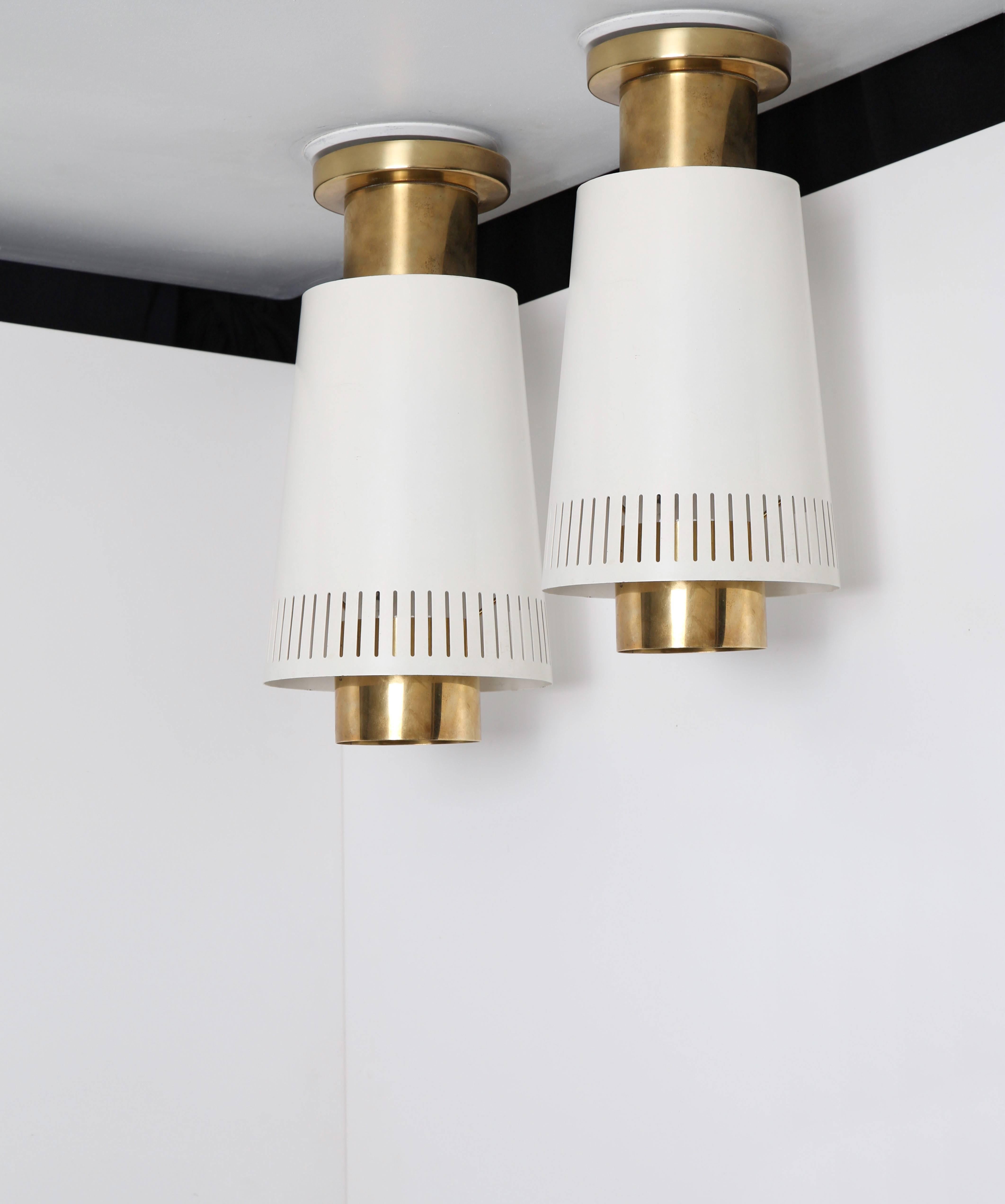 Pair of mounted ceiling lamps by Paavo Tynell, model no.9067. 

Finland, circa 1950s.
Manufacturer Idman Oy.

Impressed with manufacturer's mark [Idman]. 
Brass and white painted metal with stripe perforation pattern.

12.9 height x 6.2