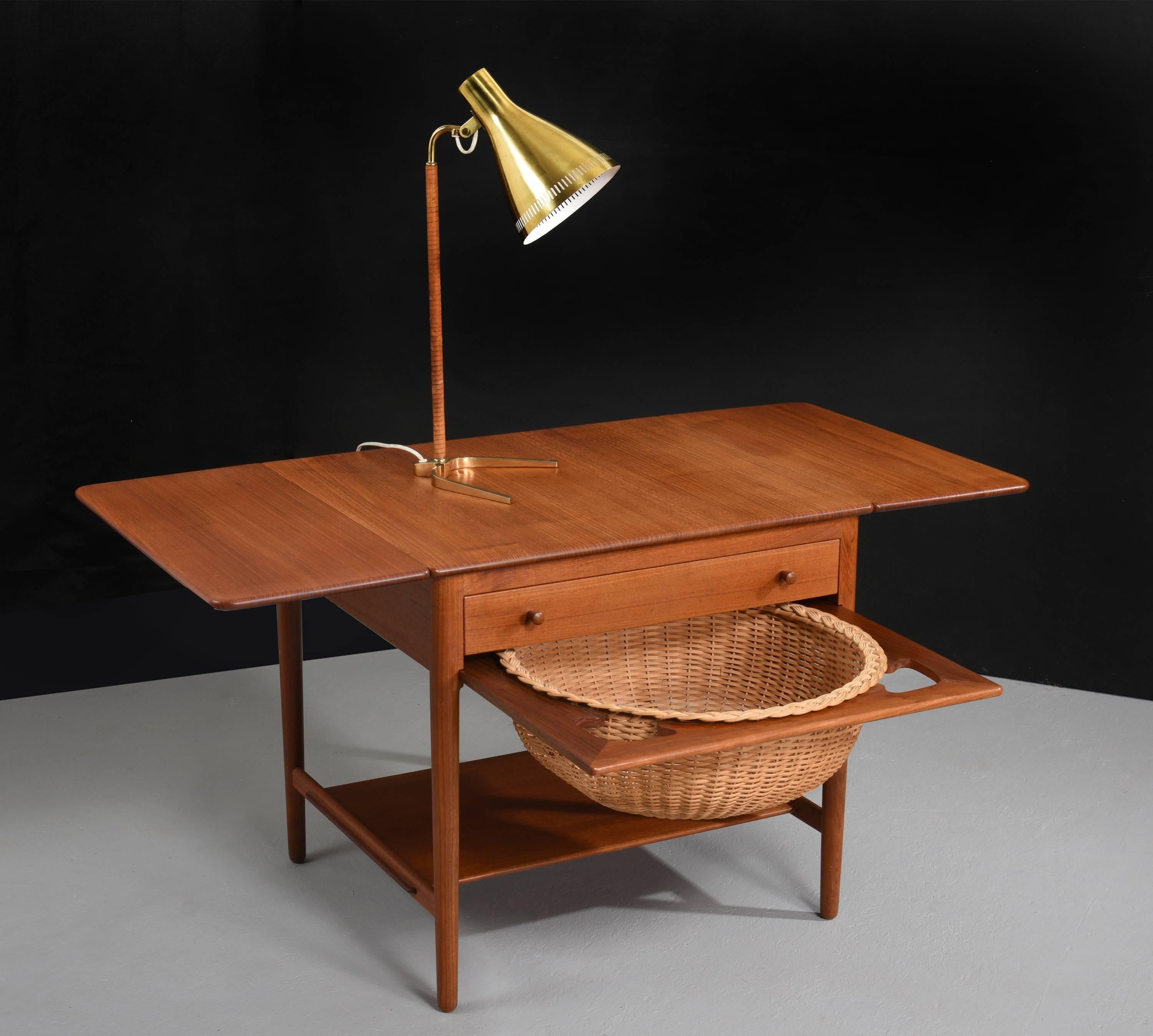 Sewing table by Hans J. Wegner for Andreas Tuck, Model AT-33,

Denmark, 1960s
Teak, cane.

Features two drop down leaves, pull out sewing basket and drawer with dividers, storage and spindles.

60 H x 67 W x 58 D cm.
119 cm wide when fully