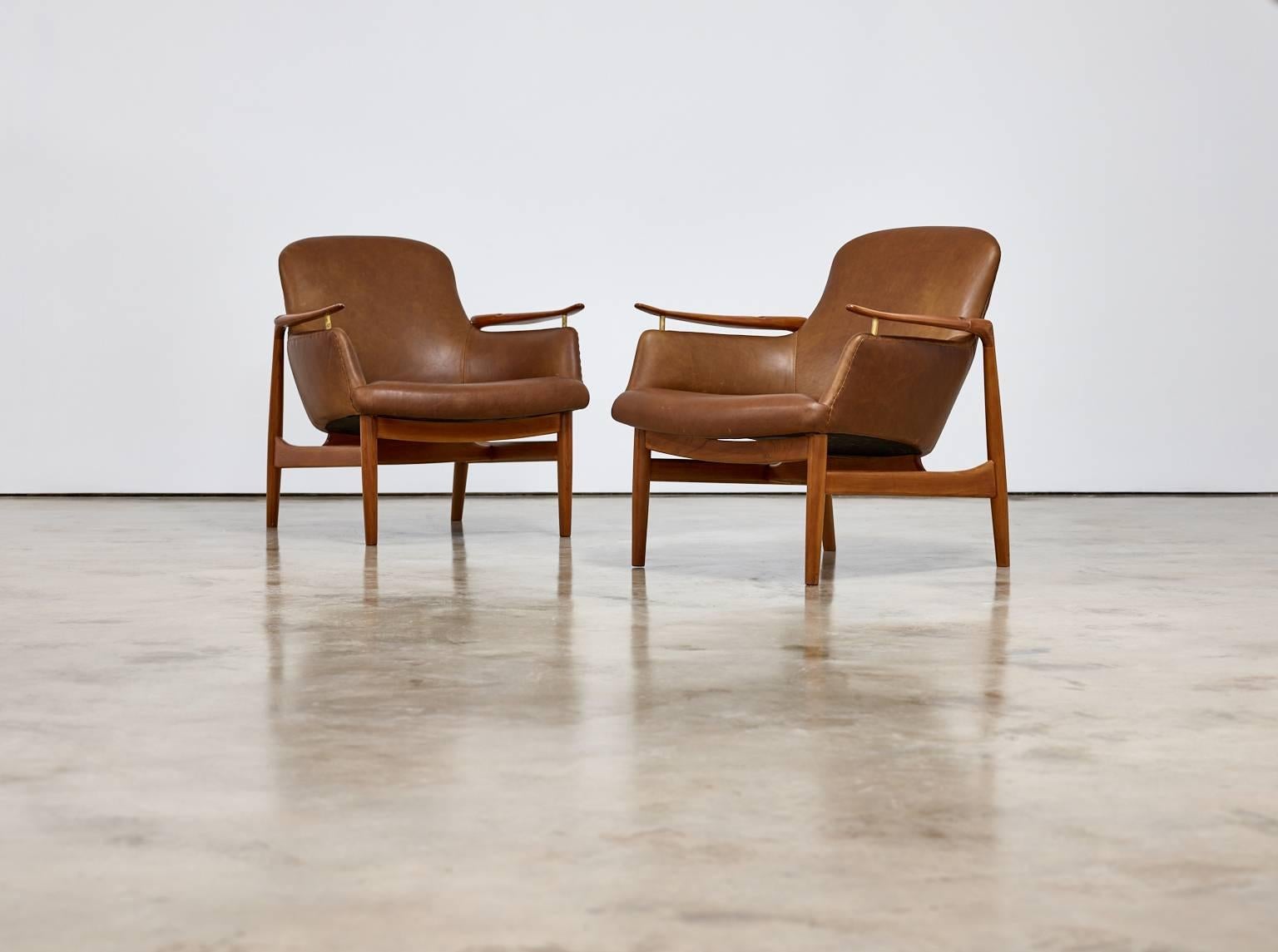 Pair of Finn Juhl armchairs, model NV53,

Copenhagen, Denmark, circa 1950s.
Cabinetmaker Niels Vodder.

Teak, leather, brass.
Each: 73.1 x 72 x 81.4 cm 
28 3/4 x 28 3/8 x 32 in.

Each underside branded and impressed with "CABINETMAKER