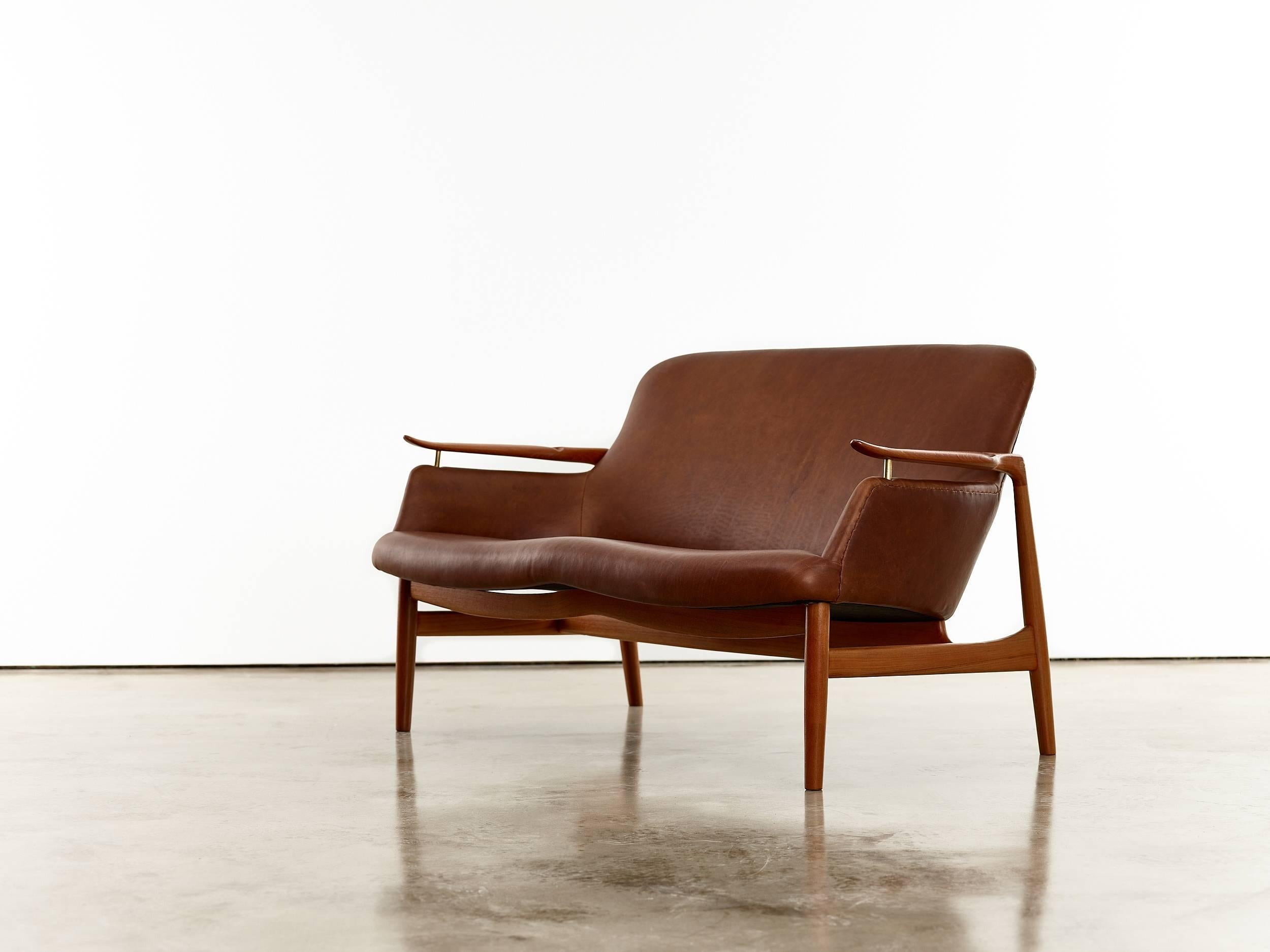 Finn Juhl two-seat sofa and lounge chairs, Model no. NV53 

Copenhagen, Denmark, circa 1950s. 

Executed by cabinetmaker Niels Vodder. 

Teak, cognac leather, brass. 

Sofa 73.8 x 128.7 x 78 cm 29 x 50 5/8 x 30 3/4 in chairs (ea) 73.1 x 72 x 81.4 cm