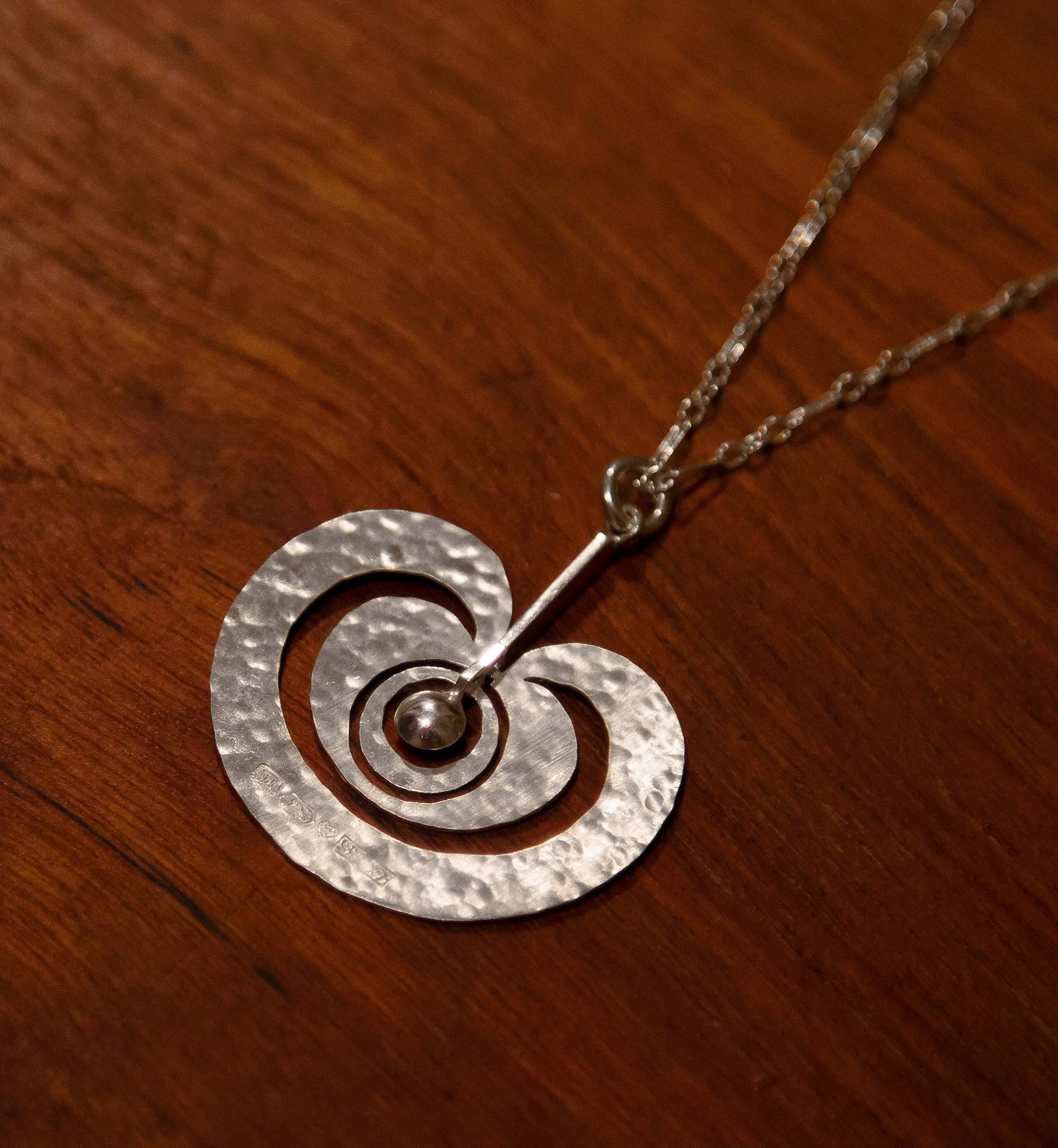 Tapio Wirkkala, sterling silver pendant.

Kultakeskus Oy, Finland, 1975.
Model was originally designed in 1972.

Handmade with hand-hammered sterling silver.
 
Impressed with following hallmarks:
Year mark X7 (1975).
Silver purity mark