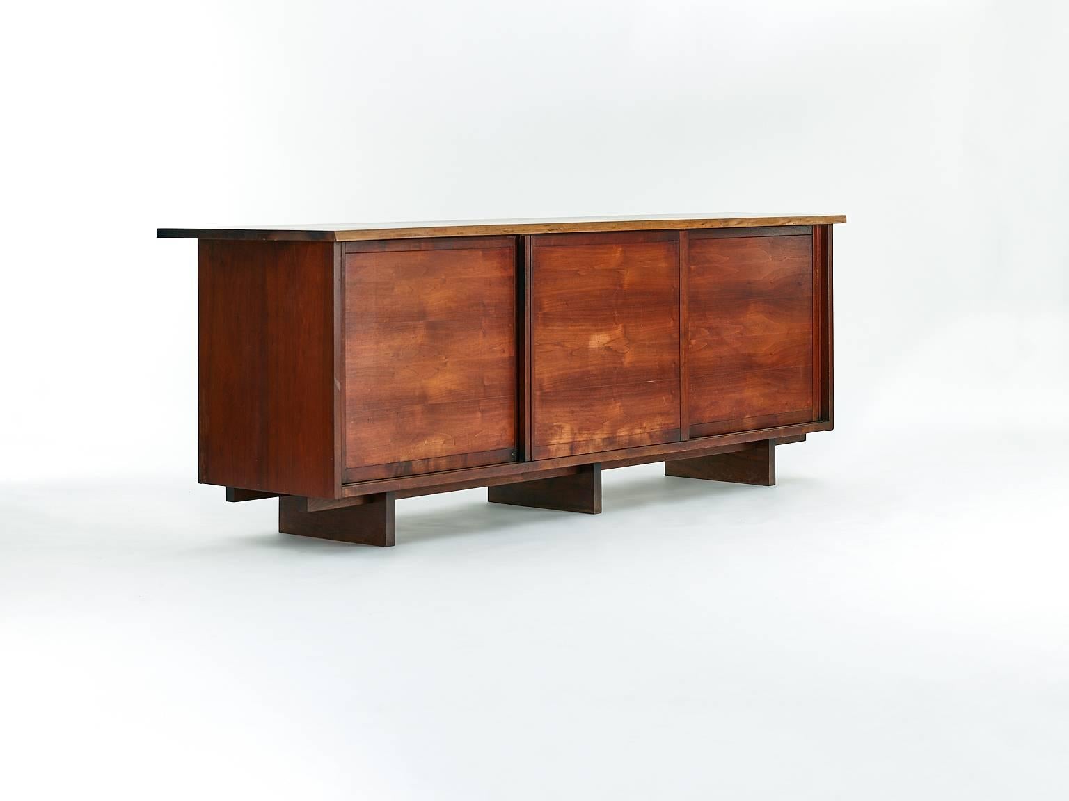 Cabinet by George Nakashima with three sliding doors.

USA, circa 1957.

American black walnut.

Dimention: 95 W x 22 D x 33 H in.

Single-slab top with one free edge.
Three sliding doors concealing four adjustable shelves and four
