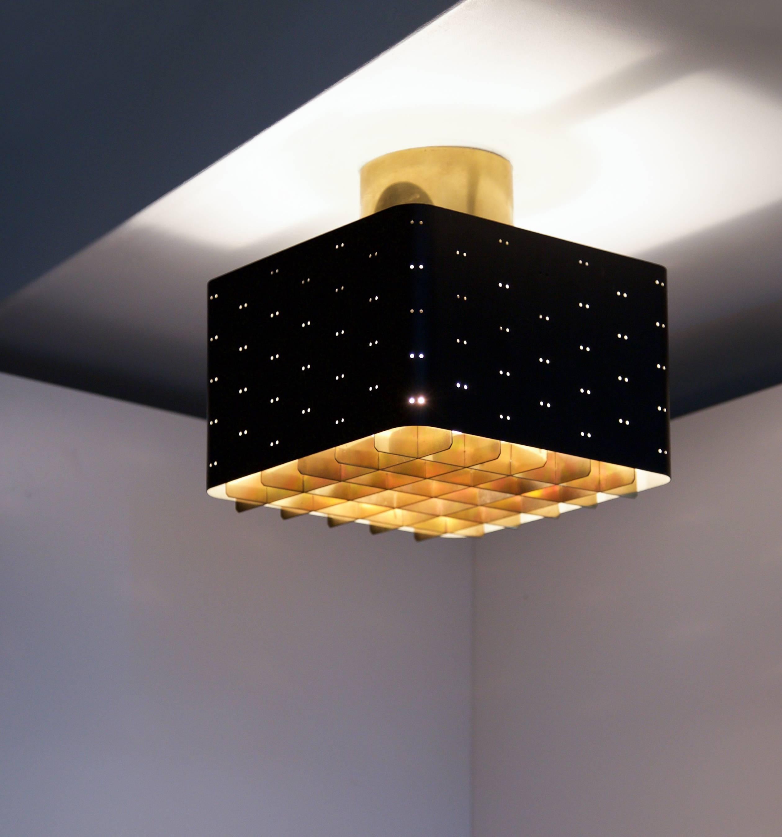 Ceiling light by Paavo Tynell, Model 9068

Finland, circa 1950s
Idman Oy, 

Measures: 24 x 24 x 23 cm.
Stamped with manufacturer's label.

Painted perforated black metal with brass ceiling ring and grid. Glass diffuser. Flush