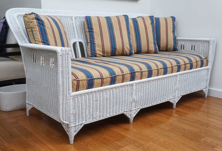 large, vintage wicker sofa, with a classic diamond pattern across the back.
cushions have been upholstered in a handsome striped fabric, with a somewhat 