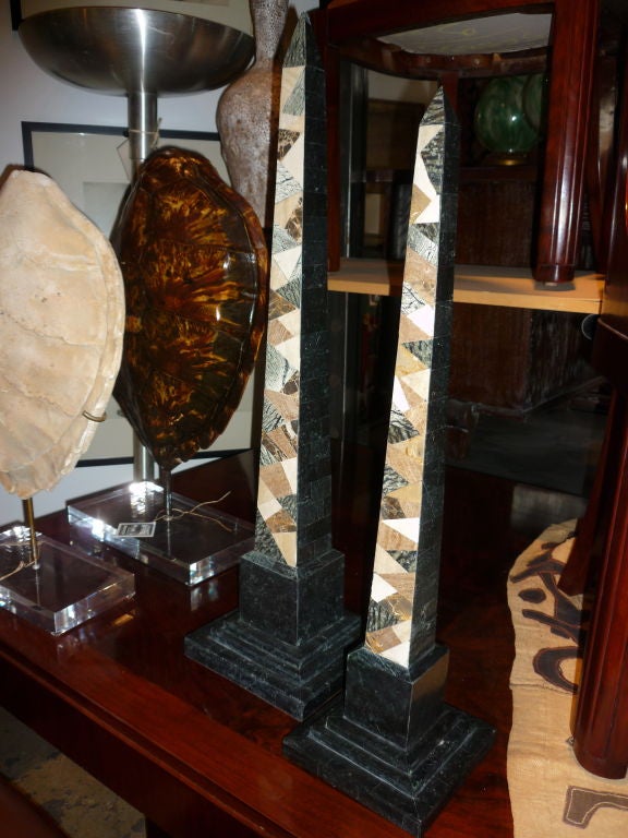 Pair of checkered marble obelisks of different heights.