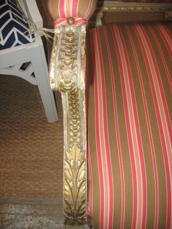 Painted and gilded settee with neoclassical laurel wreath carving on the crest rail. New striped upholstery, nail head trim, and down padding.