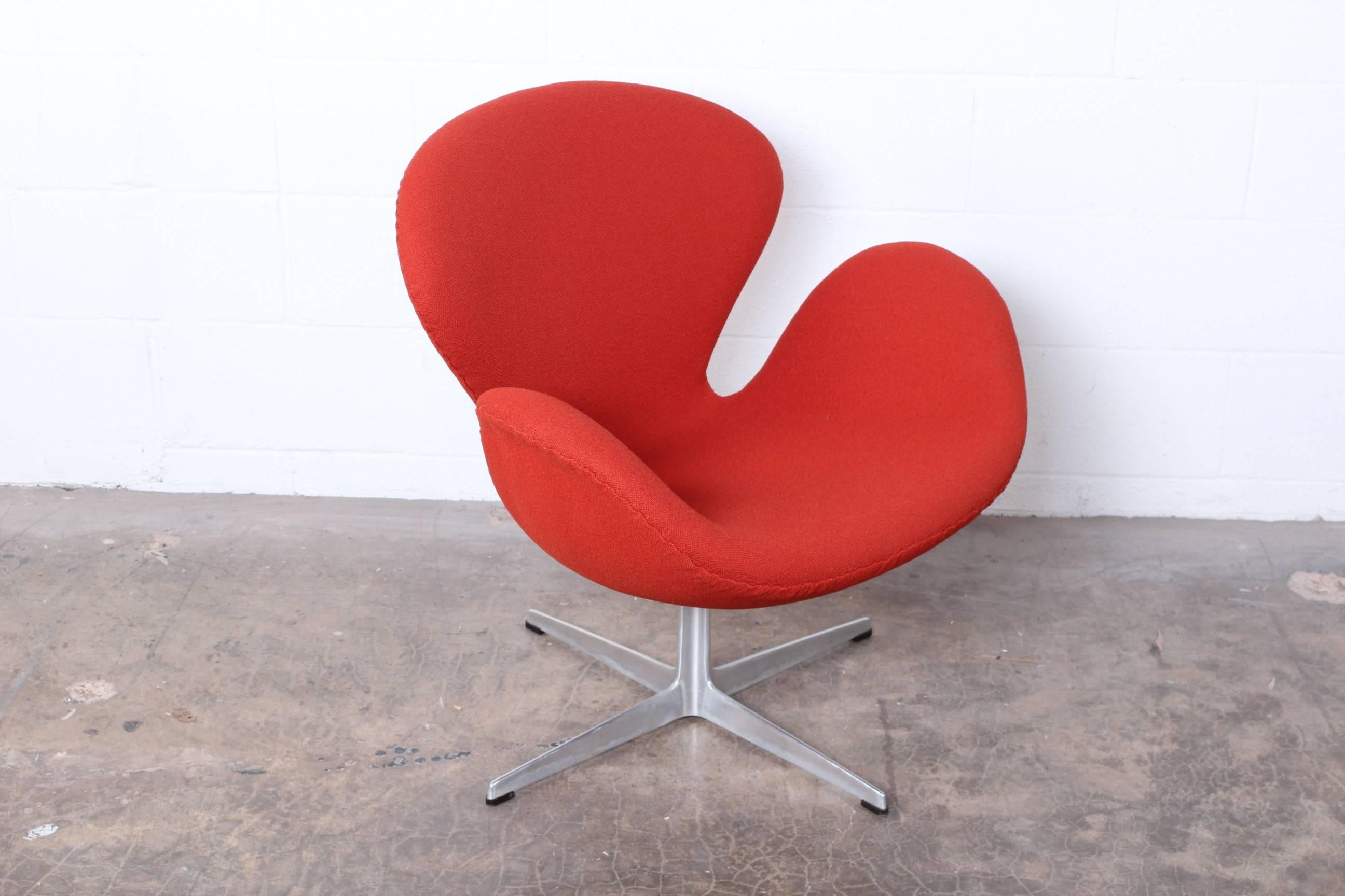 Orange swiveling Swan chair designed by Arne Jacobsen for Fritz Hansen.
