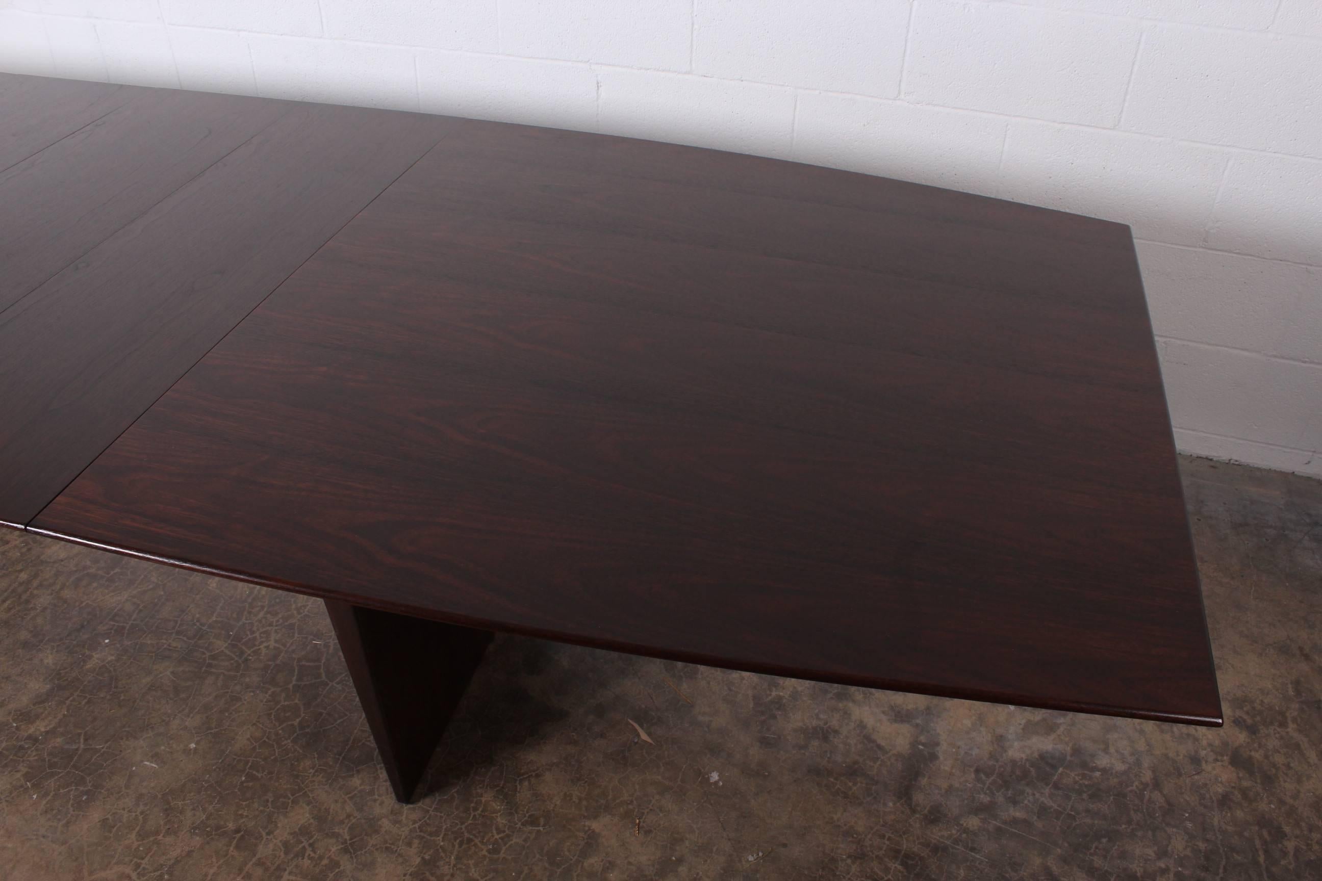 A large boat shaped walnut dining table with solid brass glides. The table measures 84