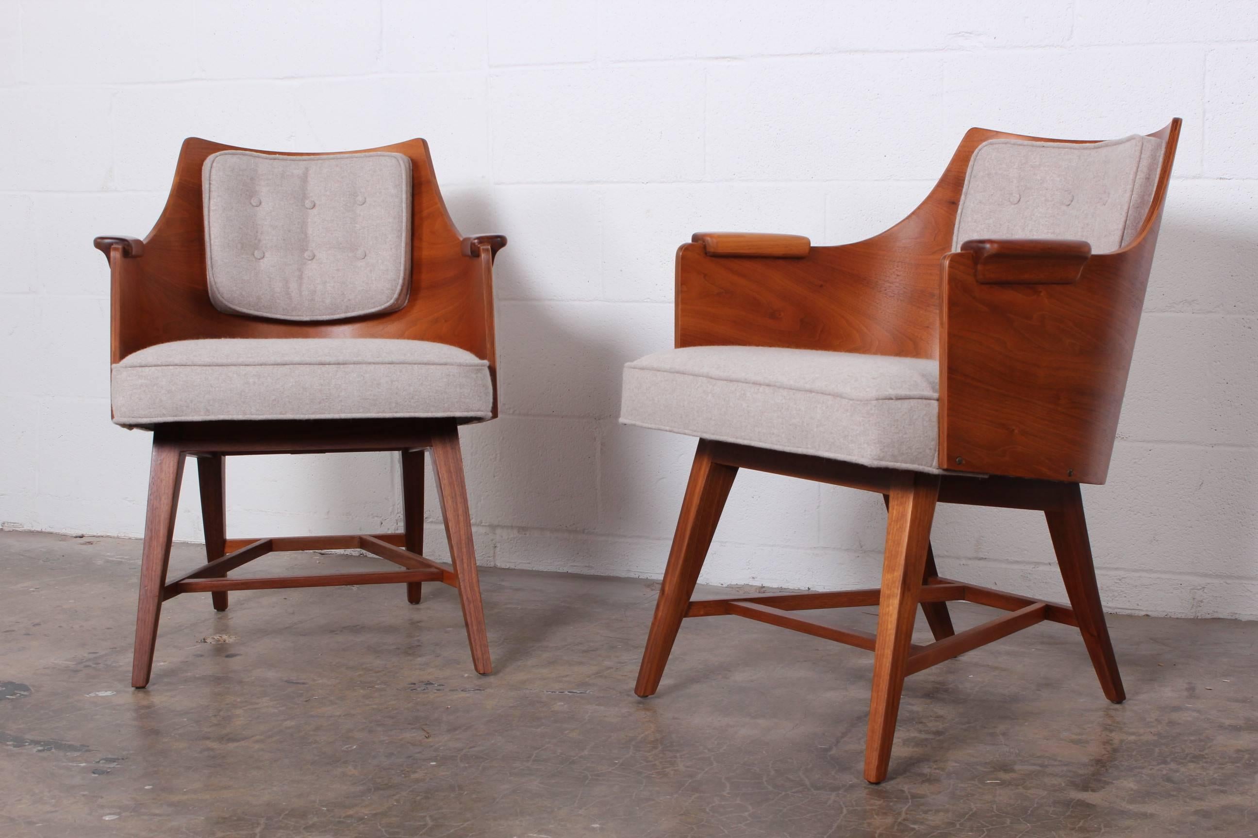 A rare pair of walnut framed lounge chairs with wool upholstery. Designed by Edward Wormley for Dunbar.