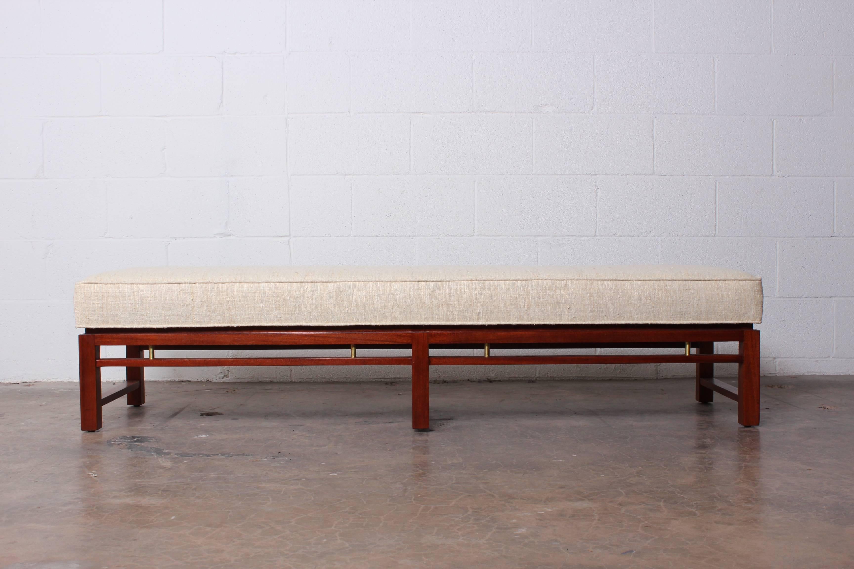 A mahogany bench with brass spacers and raw silk upholstery. Designed by Edward Wormley for Dunbar.