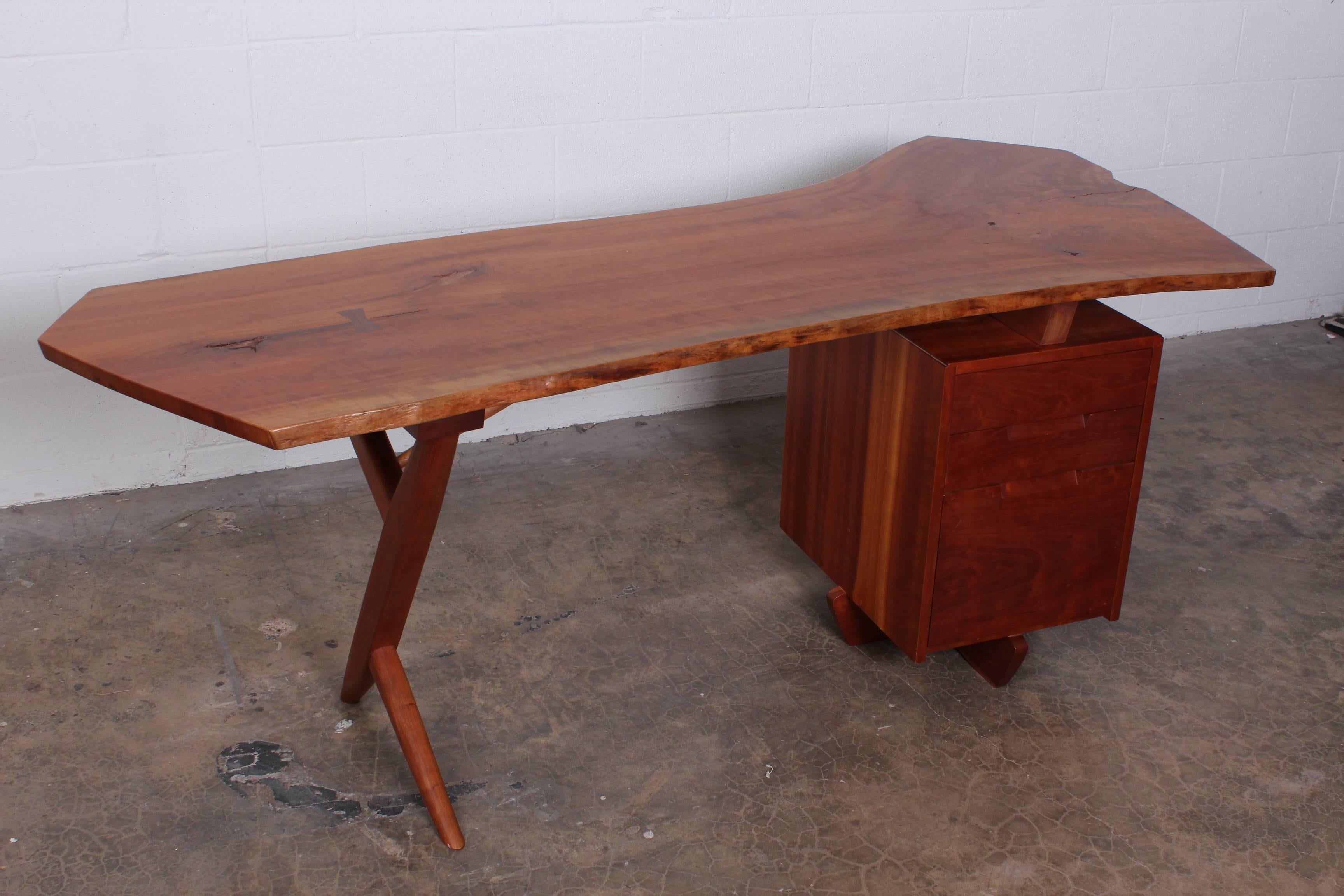 A Conoid cross-leg desk in Cherry and Hickory. Expressive cantelievered  free edge top with bowtie and extended back leg. Signed and dated by George Nakashima, 1986. 