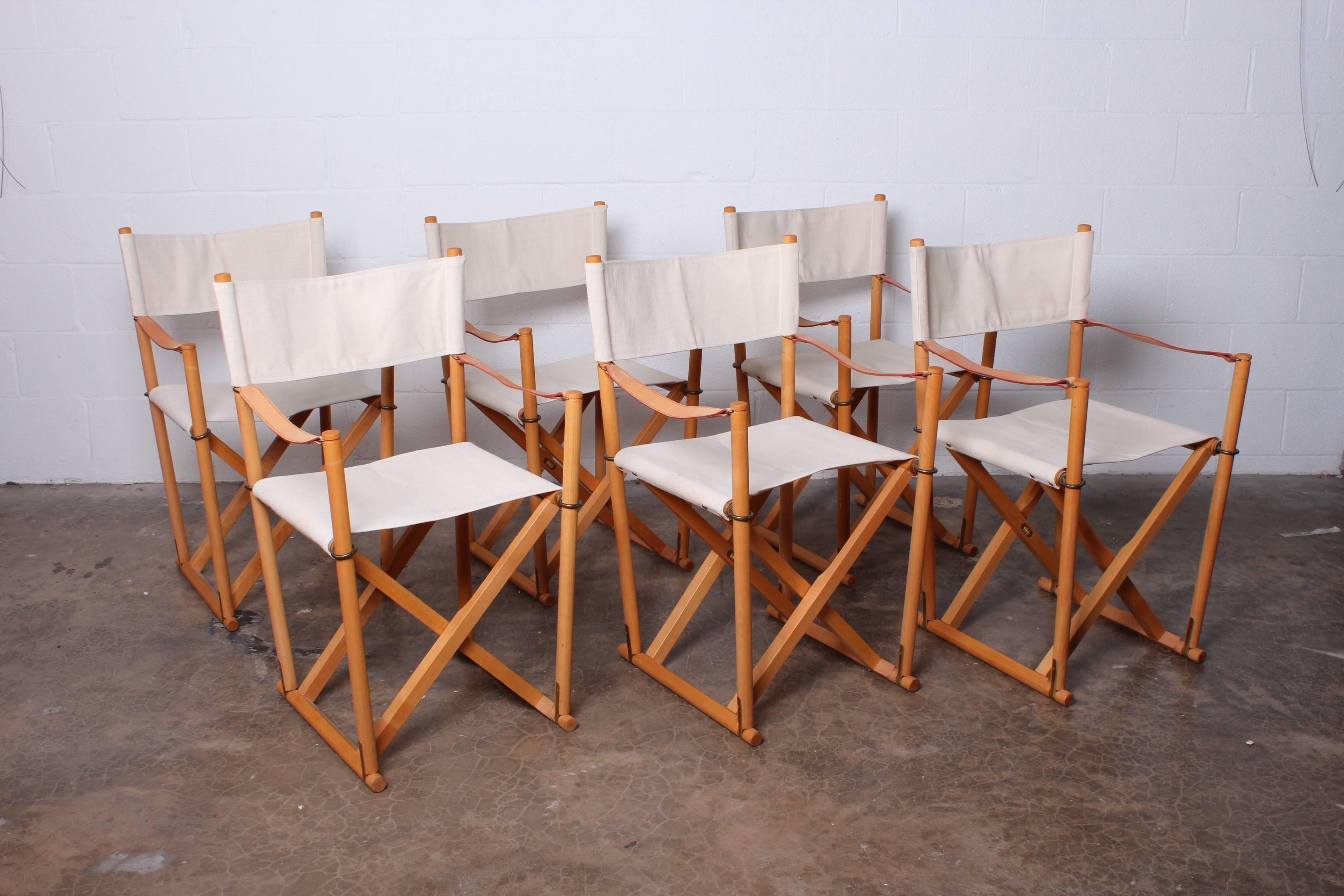 A set of six canvas covered folding safari chairs with brass hardware and storage rack. Designed by Mogens Koch. Newer production.