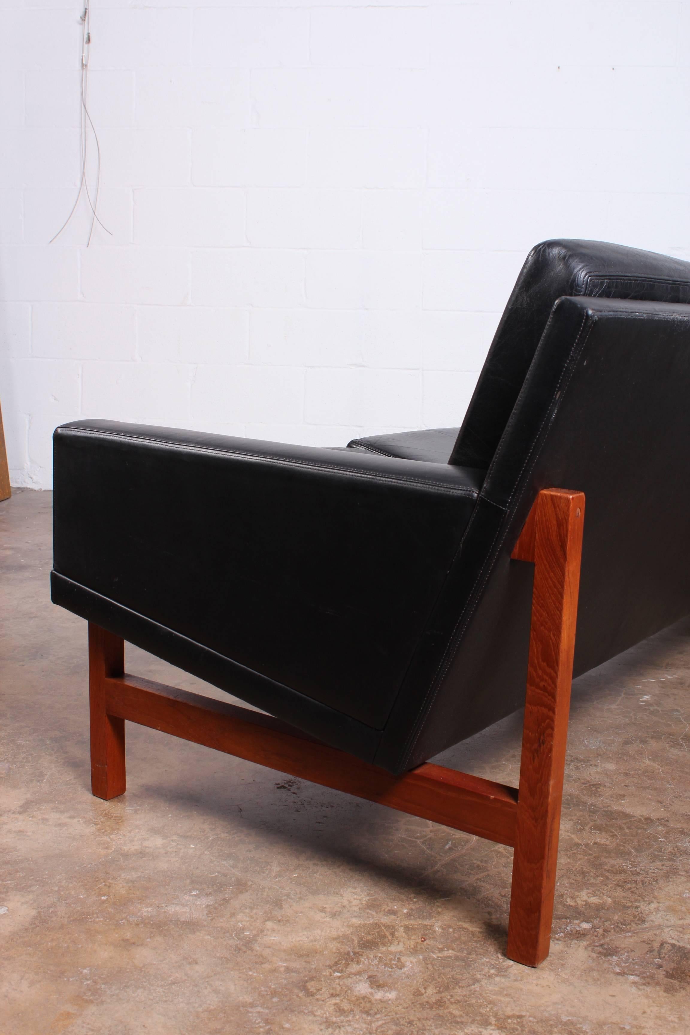 A long Danish sofa in original black leather with teak frame.