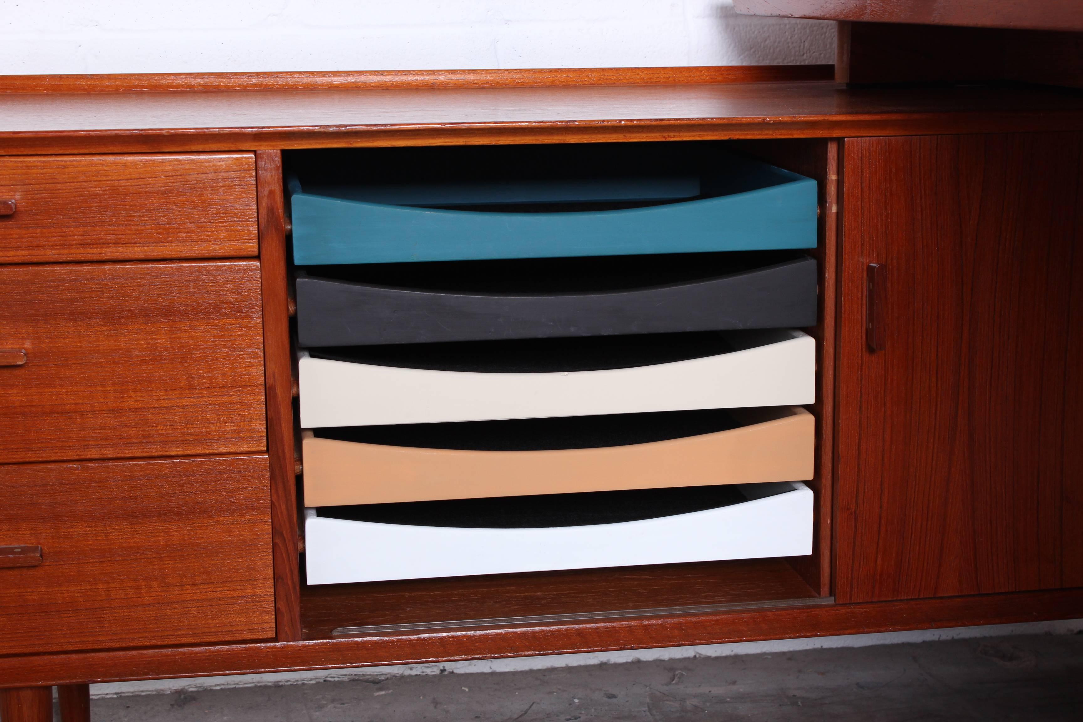 A teak desk with return designed by Arne Vodder for Sibast. Featuring original painted drawers and ample storage.
