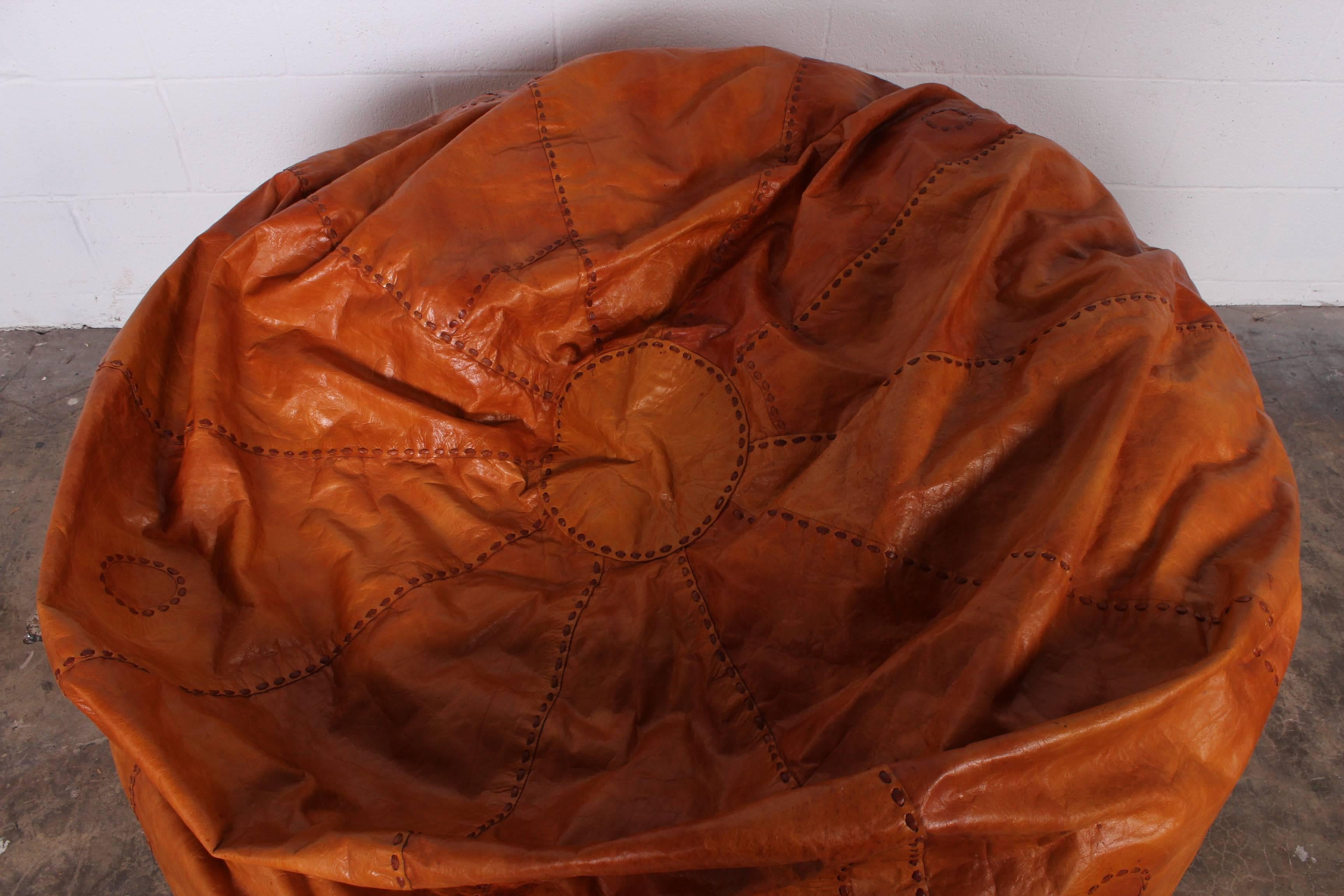 A large patinated leather beanbag with heavy stitching detail.
