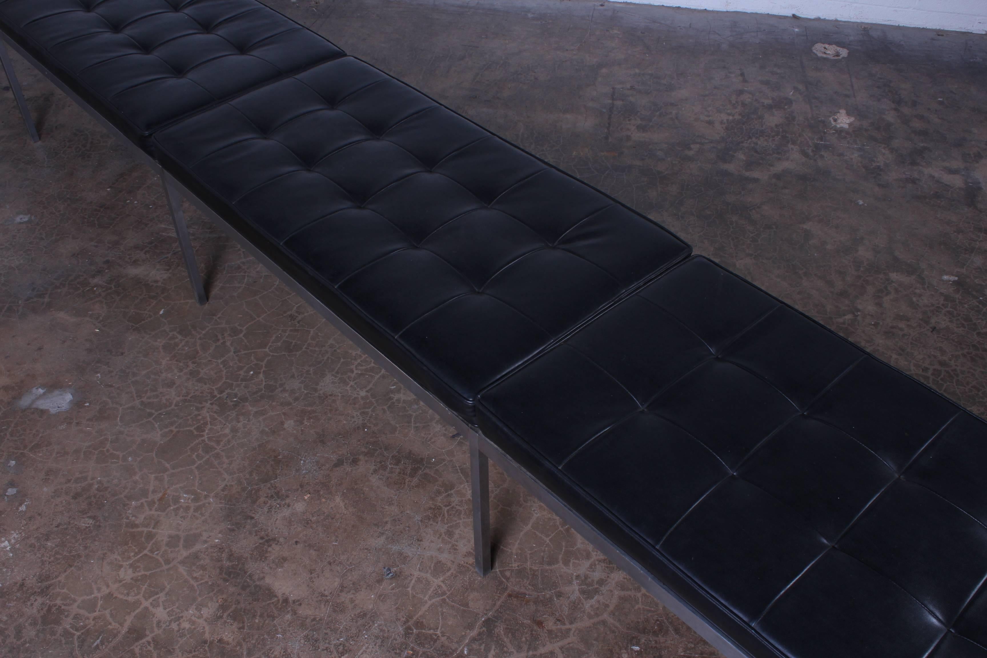 A custom twelve foot bench with stainless base and original black vinyl upholstery. Designed by Florence Knoll for Knoll.