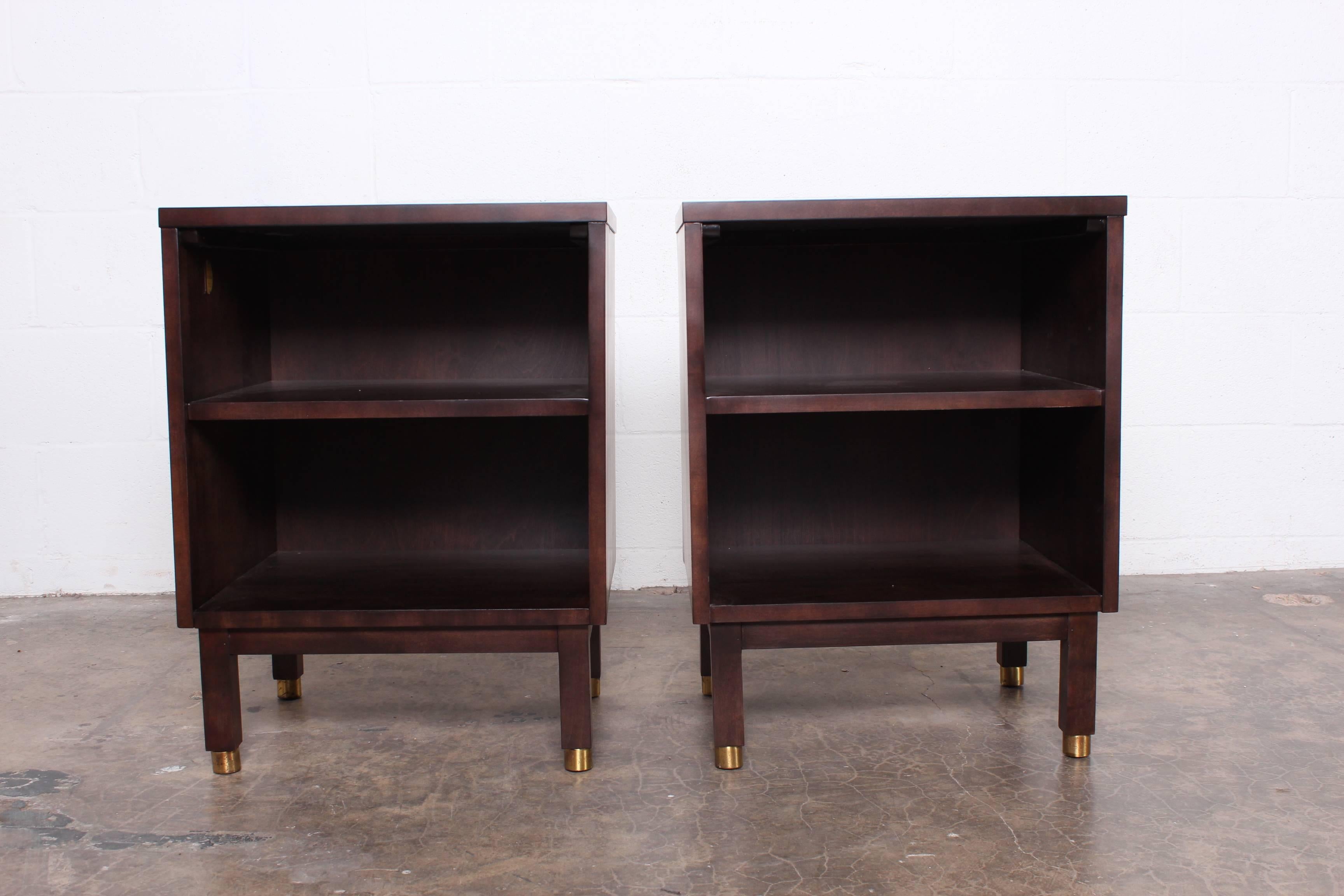 A pair of bedside tables in walnut with laminate tops and brass feet. Designed by Edward Wormley for Dunbar.
