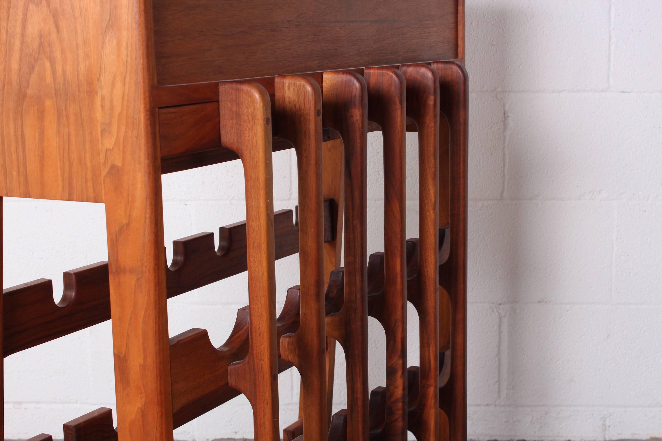 A beautifully crafted wine rack with built in drop front cabinet and three drawers.