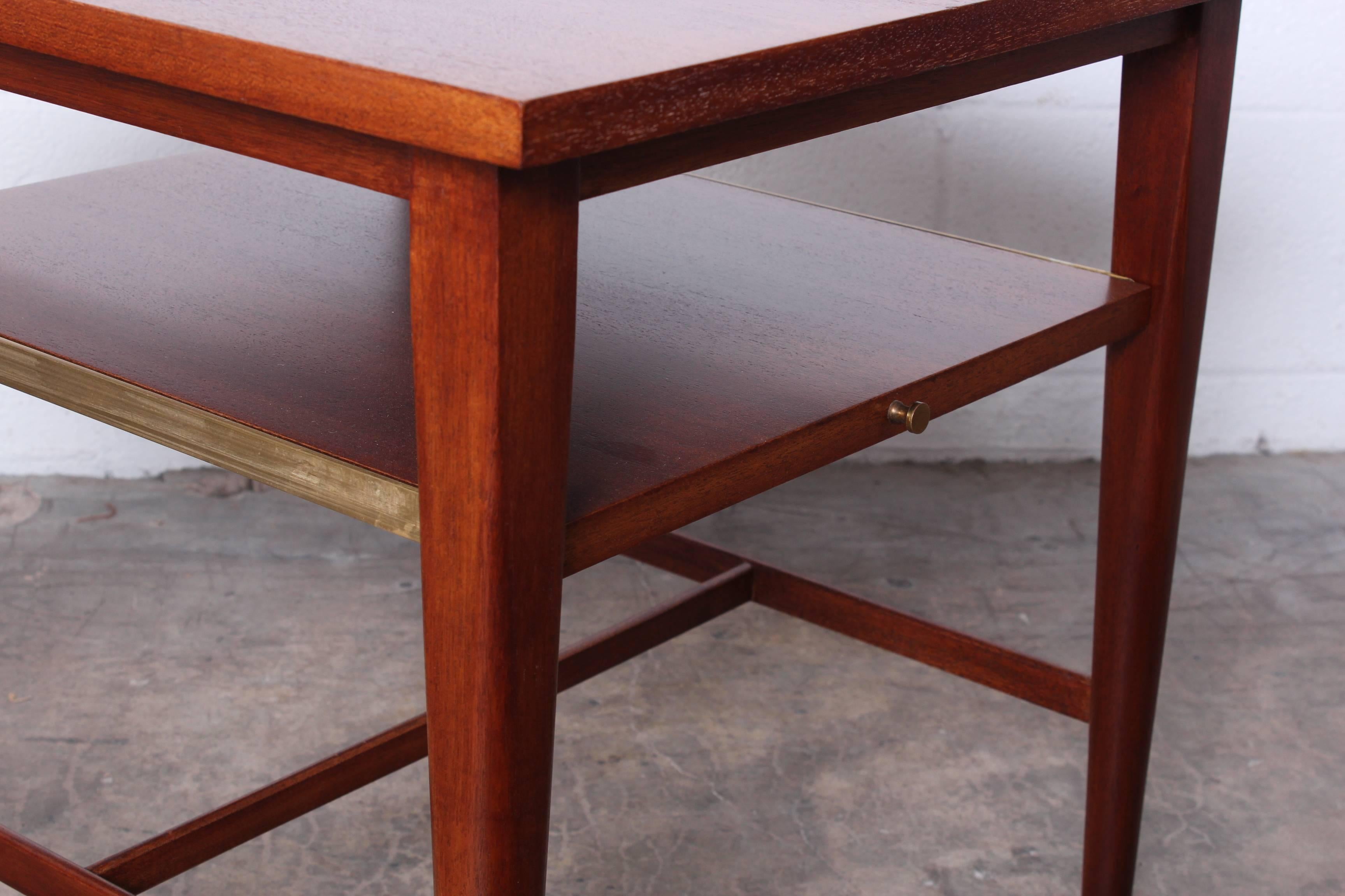 A pair of mahogany tables with slide out shelves. Designed by Paul McCobb for Calvin.