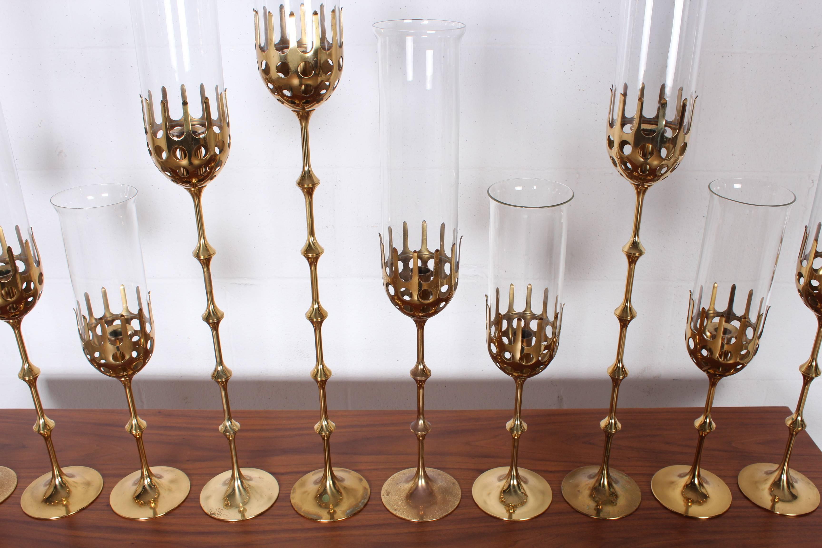 A large and impressive collection of brass candlesticks with glass hurricanes. Designed by Bjorn Winkled, each with maker impression to bottom.