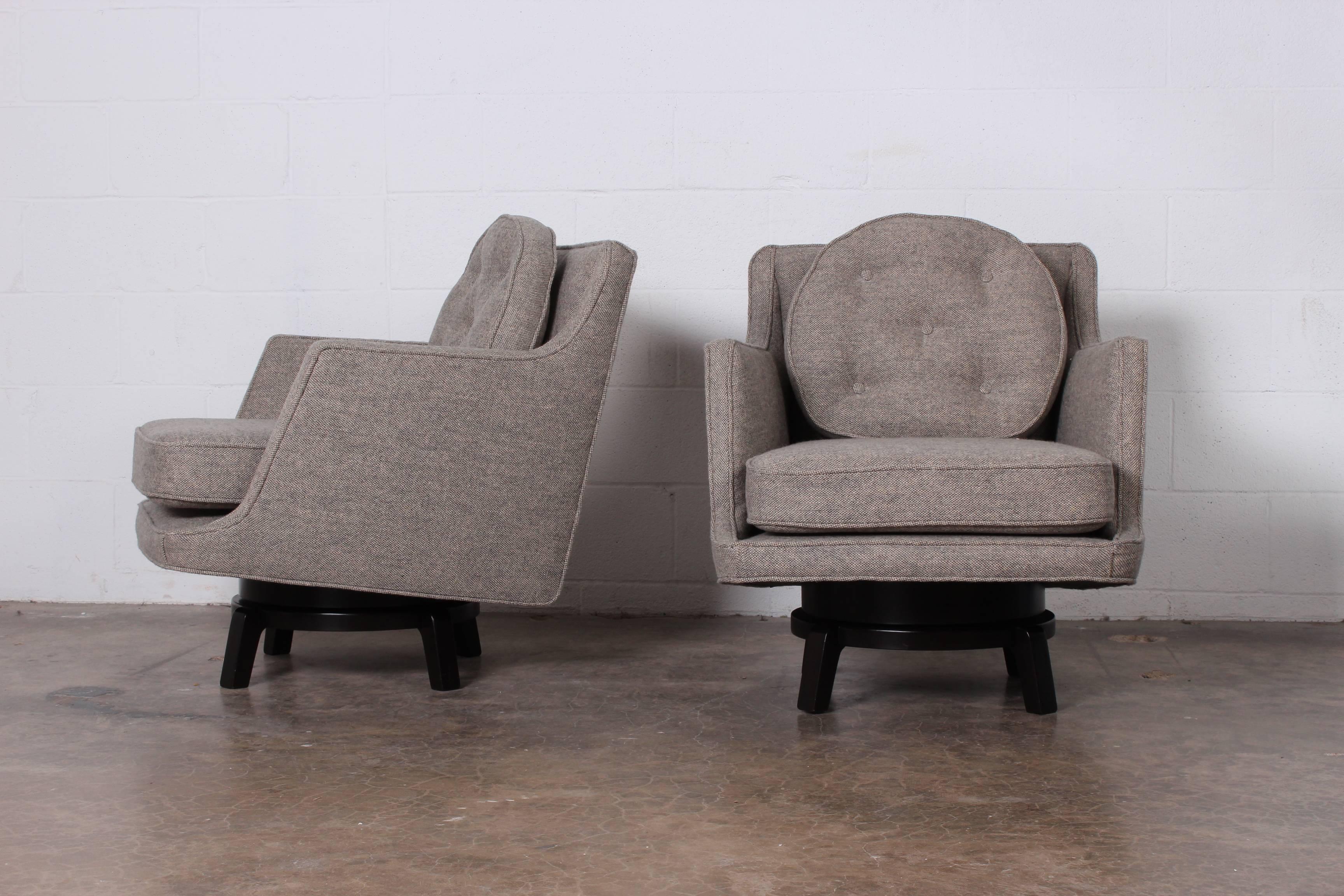 A pair of swiveling lounge chairs on mahogany bases. Designed by Edward Wormley for Dunbar.