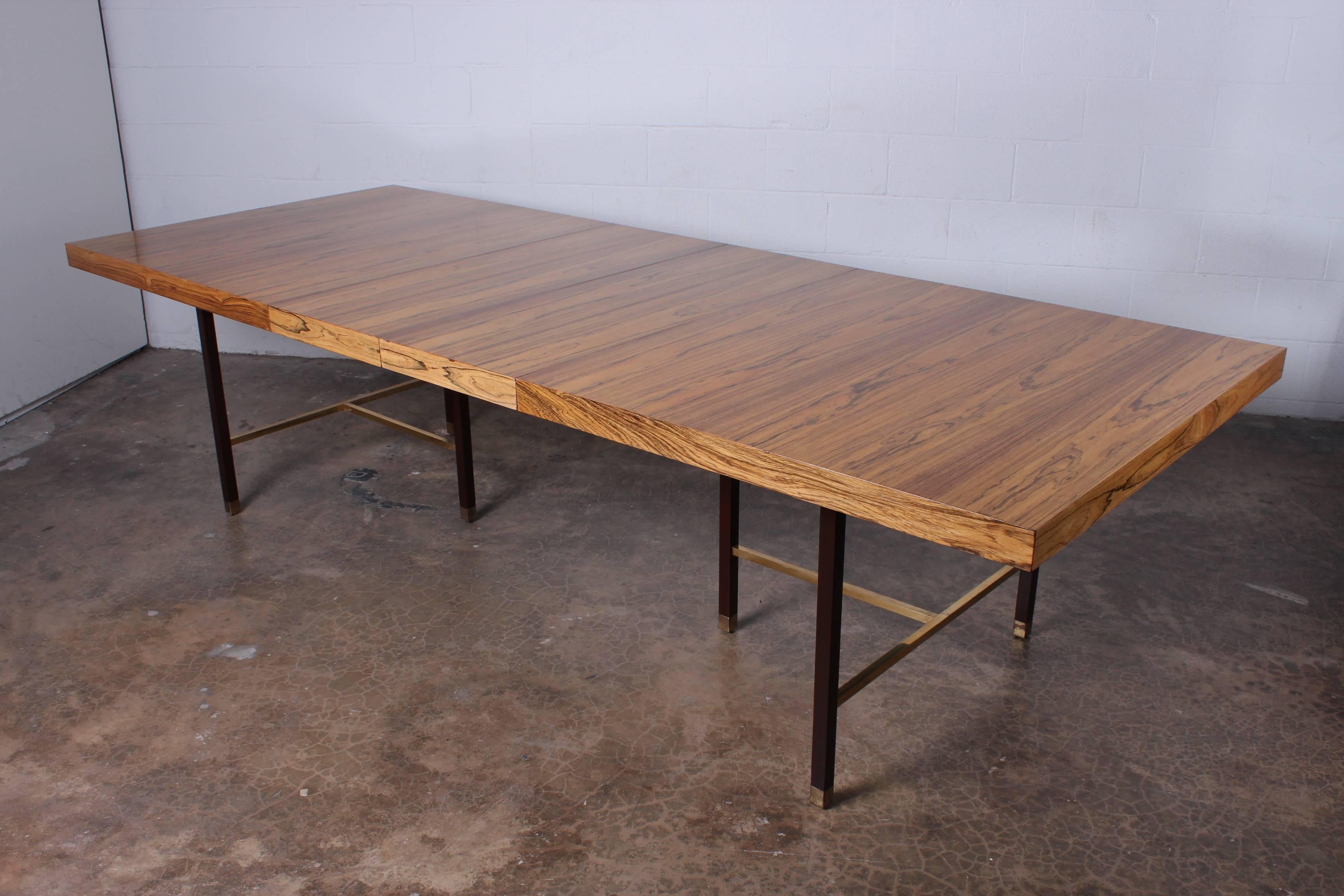 A large bleached rosewood dining table on mahogany base with brass stretchers. Designed by Harvey Probber. Measures: 112