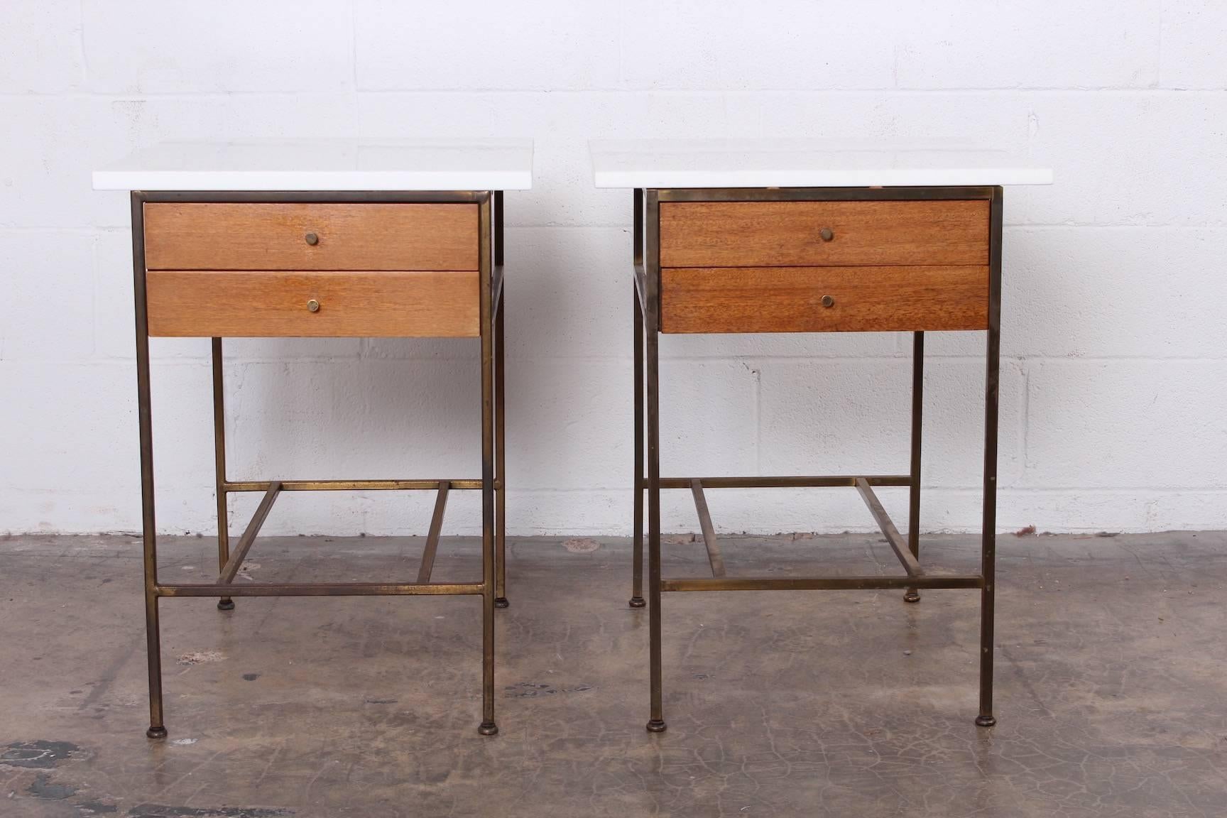 A pair of brass and mahogany bedside tables with original Vitrolite tops. Designed by Paul McCobb for Calvin.