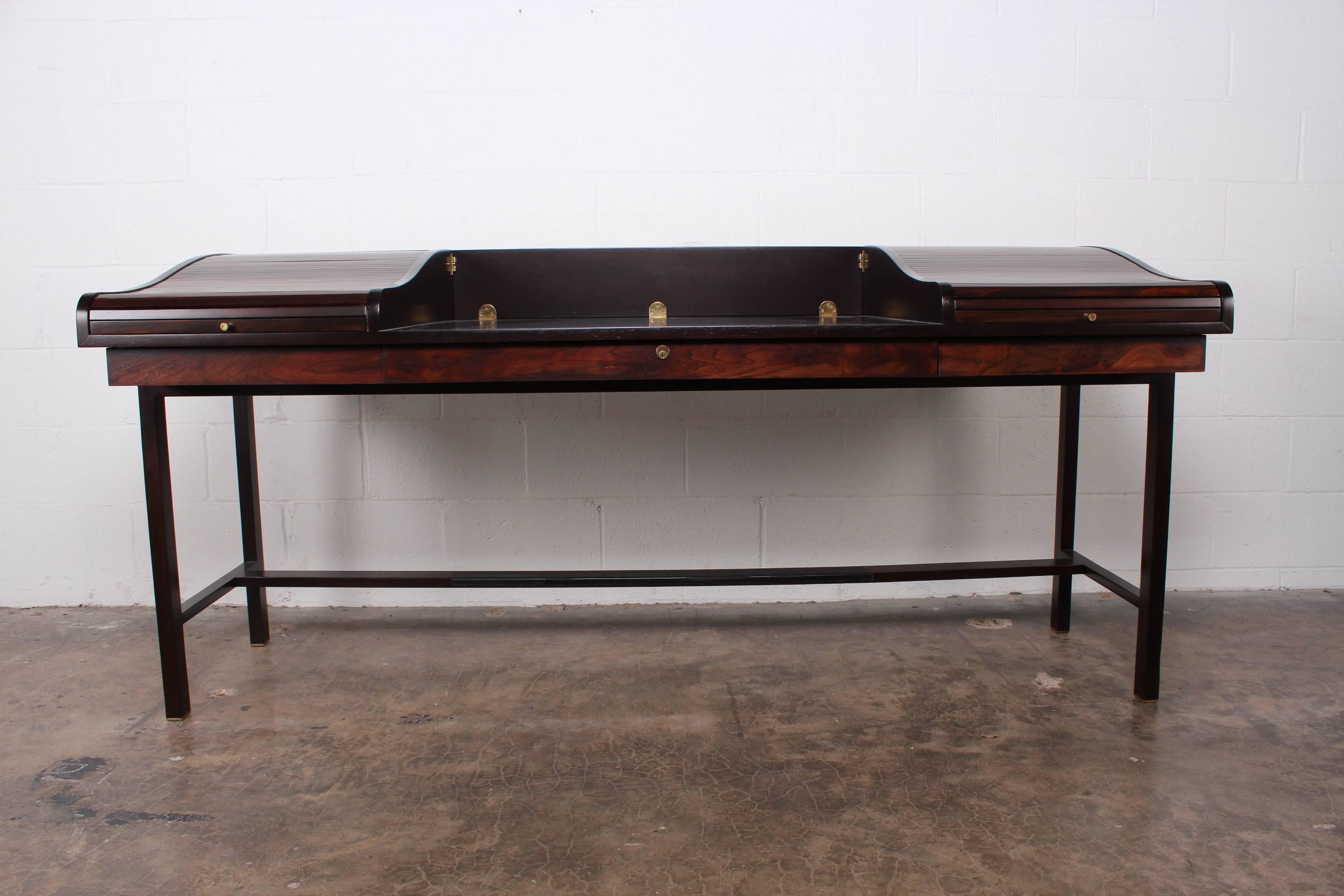 A rosewood tambour roll top desk with brass feet and leather trim. Designed by Edward Wormley for Dunbar.