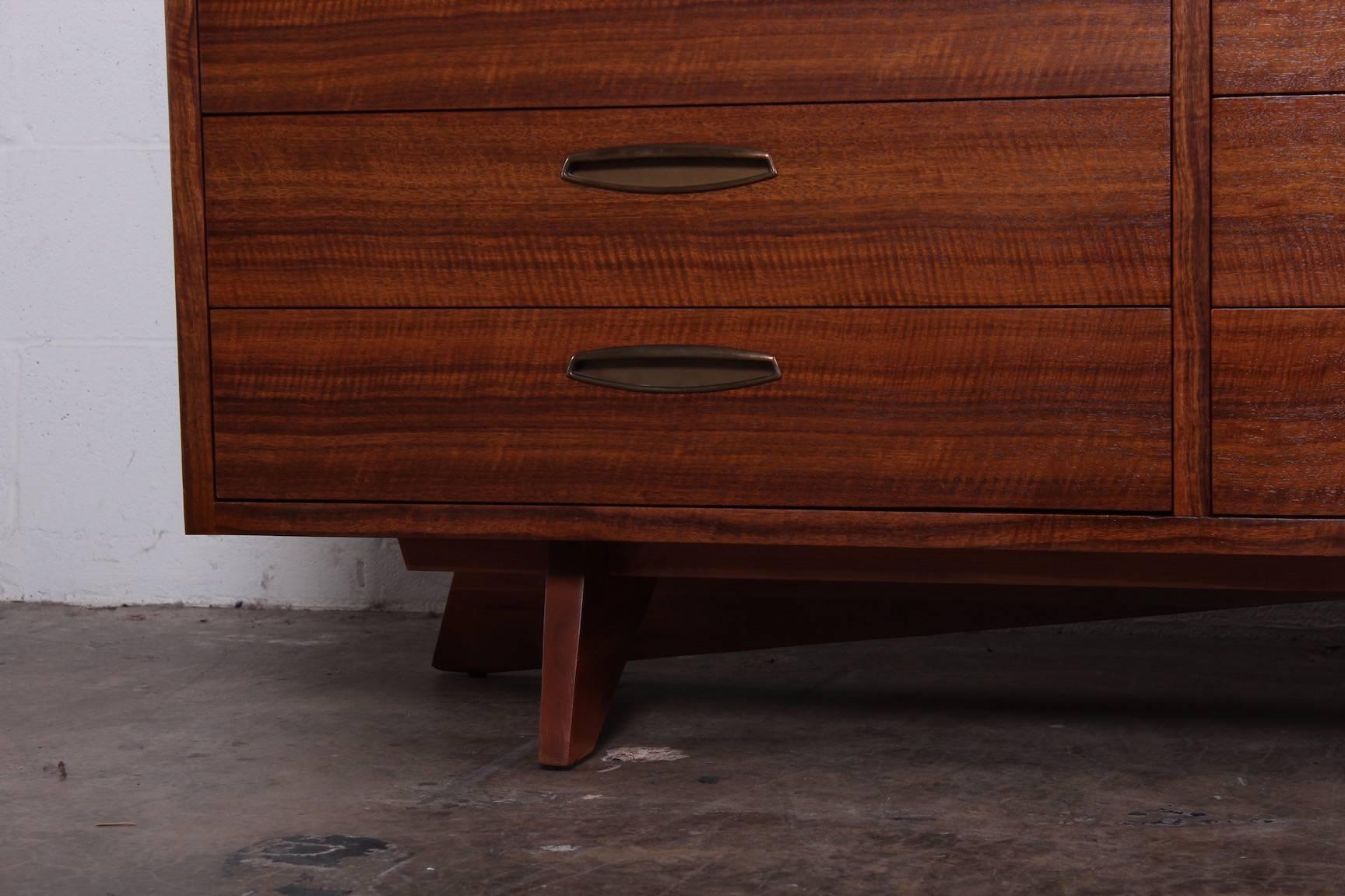 A walnut chest of drawers with brass hardware. Designed by George Nakashima for Widdicomb.