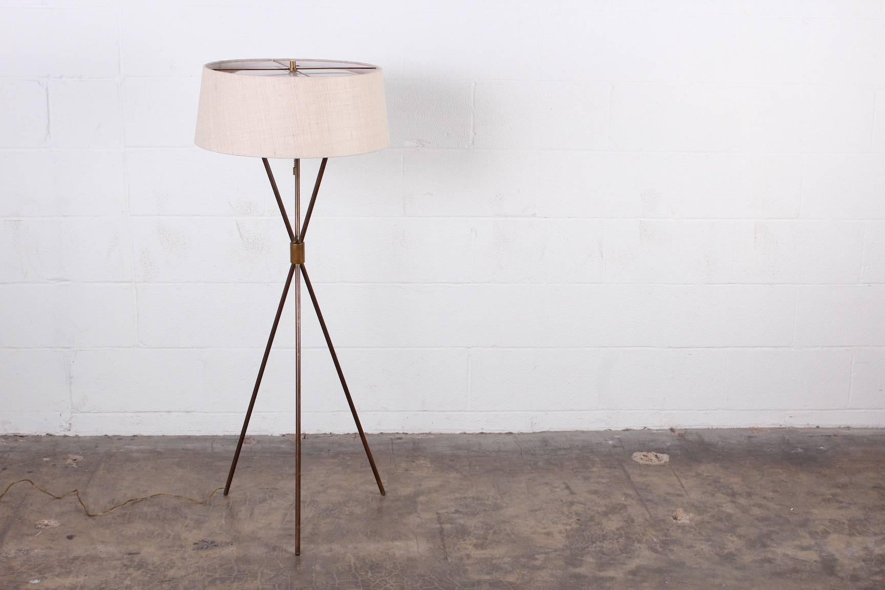 A beautifully patinated brass tripod floor lamp designed by T.H. Robsjohn-Gibbings for Hansen. New raw silk shade.