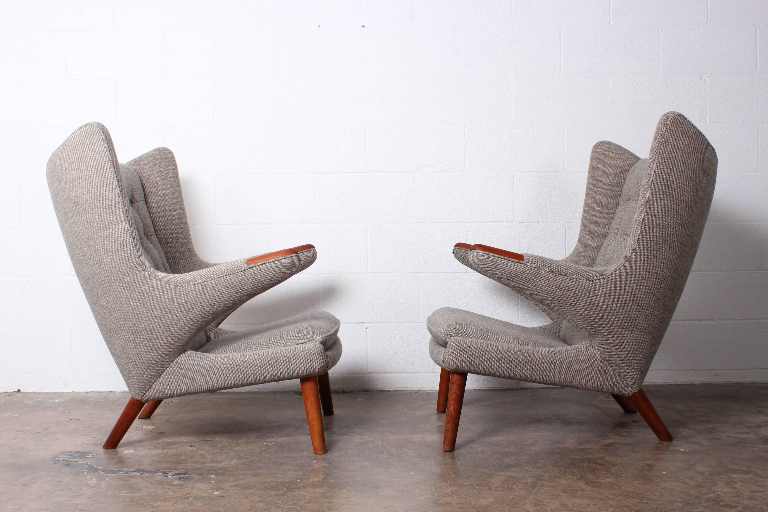 A matching pair of Papa bear chairs designed by Hans Wegner for AP Stolen. The chairs have been reupholstered with Maharam wool. The straps and teak retain their original patina.