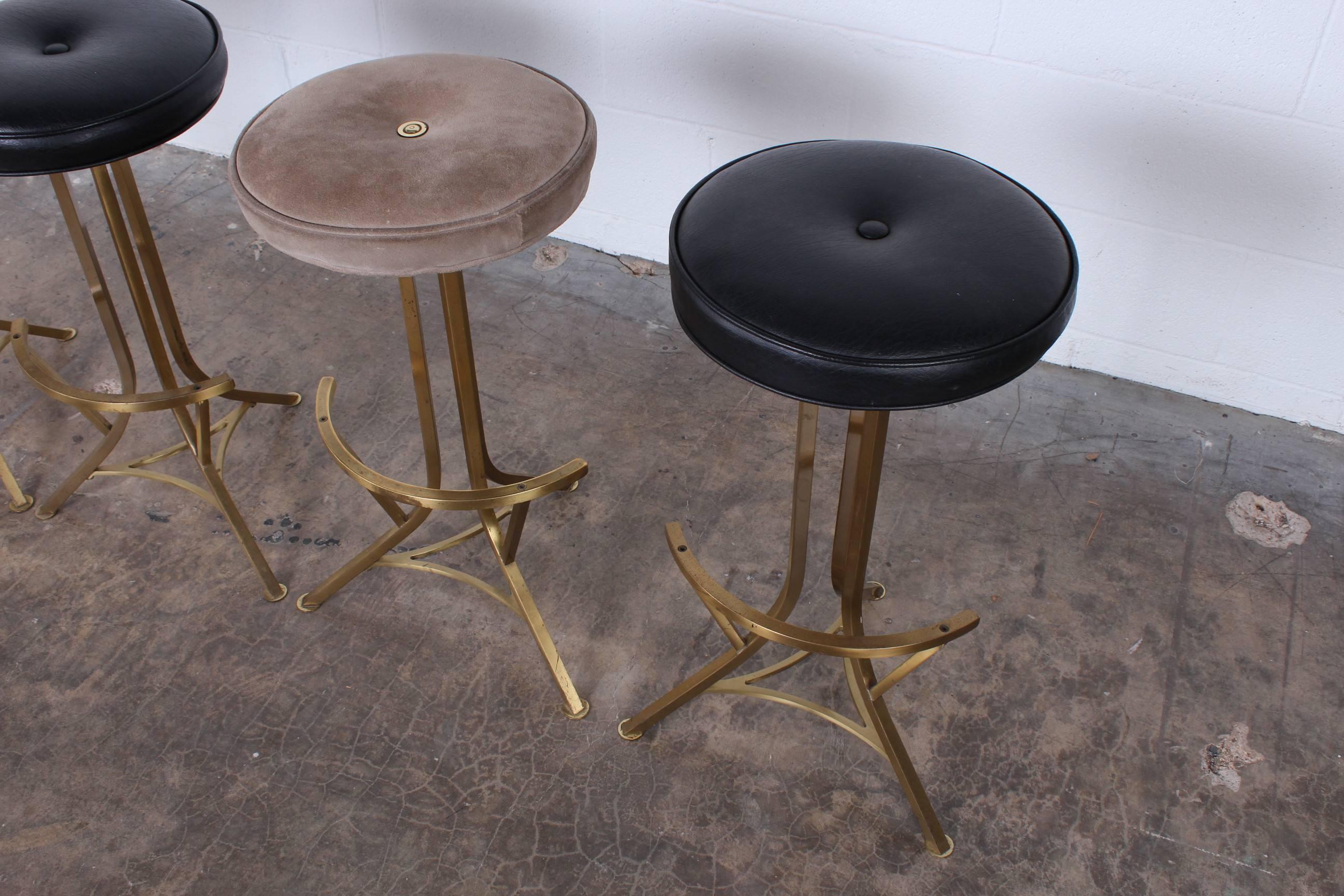 A set of four brass based barstools by John Stewart with swivel tops.