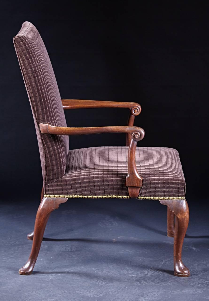 A pair of George II library chairs with rectangular upholstered backs and seats on four cabriole legs ending in platform padded feet and with serpentine and scrolled carved arms. These chairs retain 75% of their original webbing and padding from the