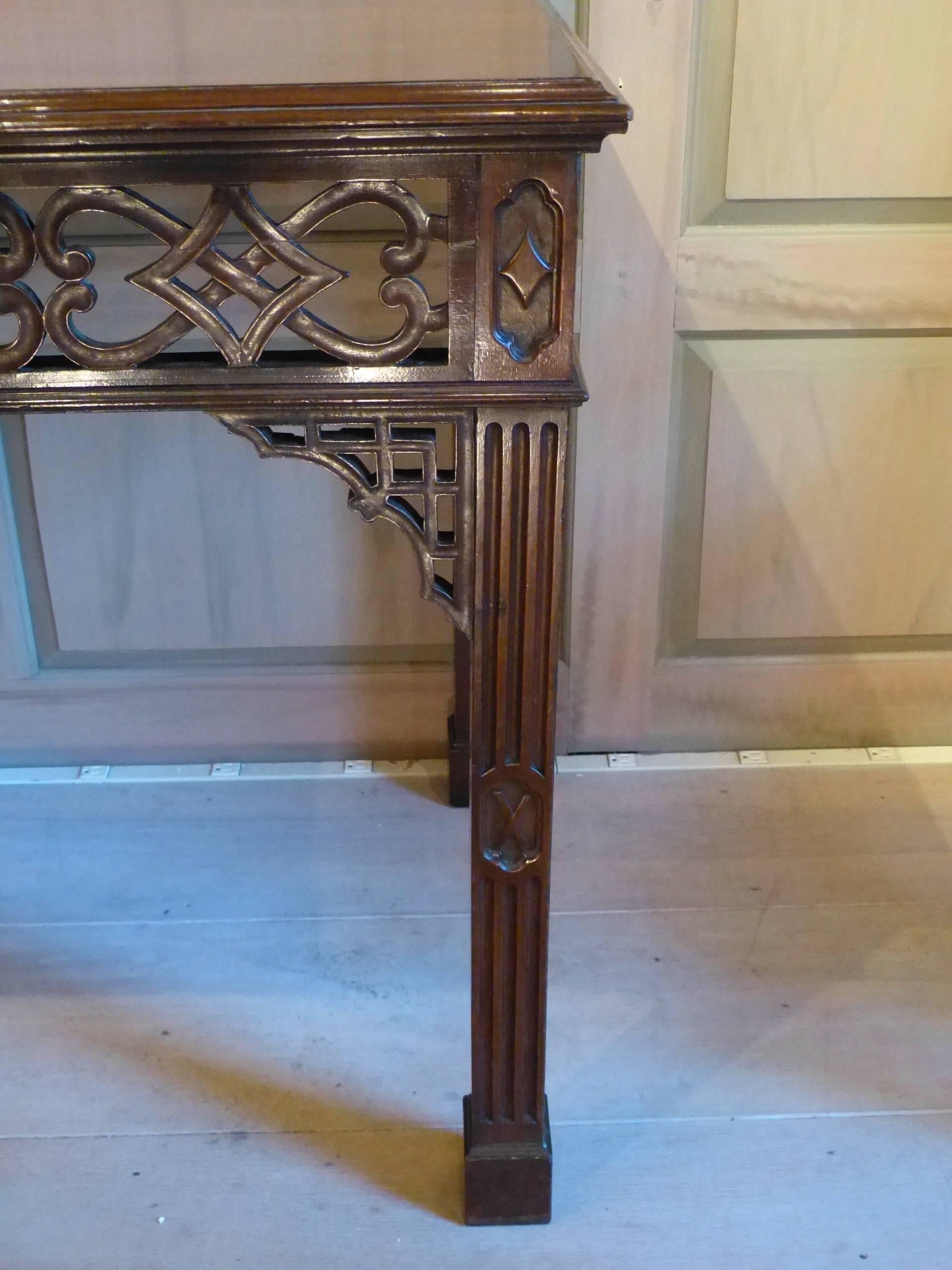 A very fine quality English Chinese Chippendale period mahogany table with open fretwork to three sides, on fluted legs supporting a fine flame mahogany single board, circa 1765.