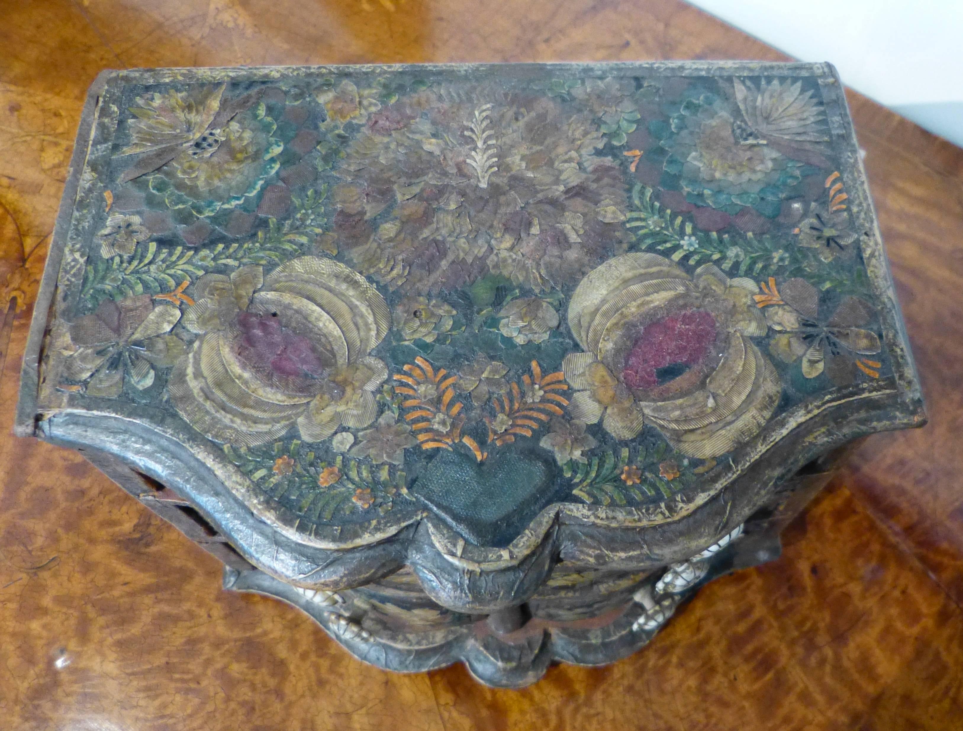 A rare and unusual German rococo serpentine front laca povera (decoupage) miniature chest having floral appliques to the front, pomegranate and hearts to the top. The pomegranate signifying abundance or fertility, the hearts as love. Probably a