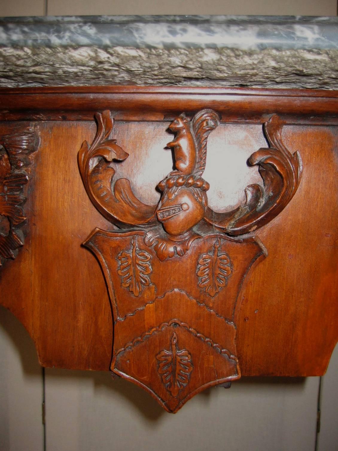 A fine quality walnut carved console table with marble top, the central panel coat of arms with inverted band and a helmet surmounted by a squirrel. The squirrel theme is repeated on the carved knees together with acorns. The table possibly either