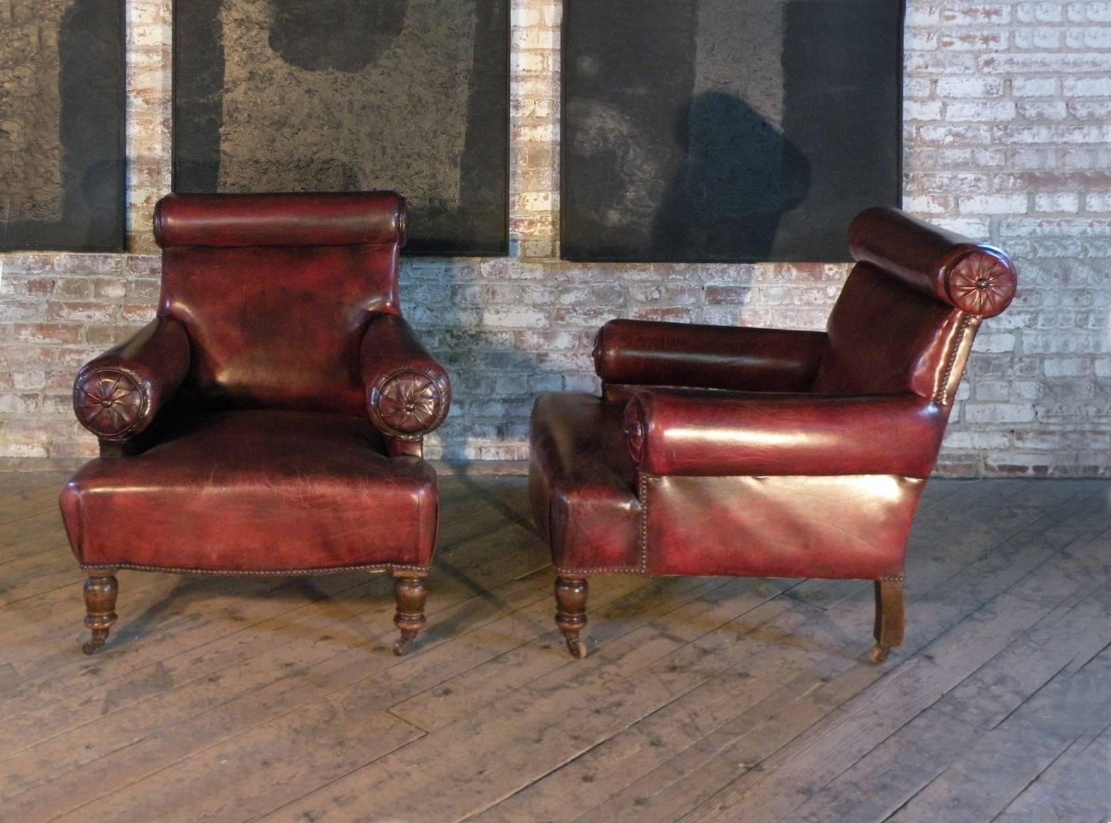 A generously sized pair of English lounge or club chairs of unusual design, early 20th century, mahogany, covered in oxblood-red leather.
Very comfortable proportions, turned front legs and square, slightly curved back legs, on casters, evidence of