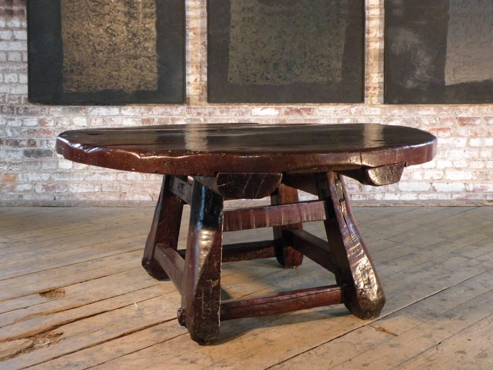Insolite, frappant, audacieux.
Grande table basse ronde avec un plateau massif soutenu par une base carrée évasée construite à partir de poutres en bois grossièrement taillées.